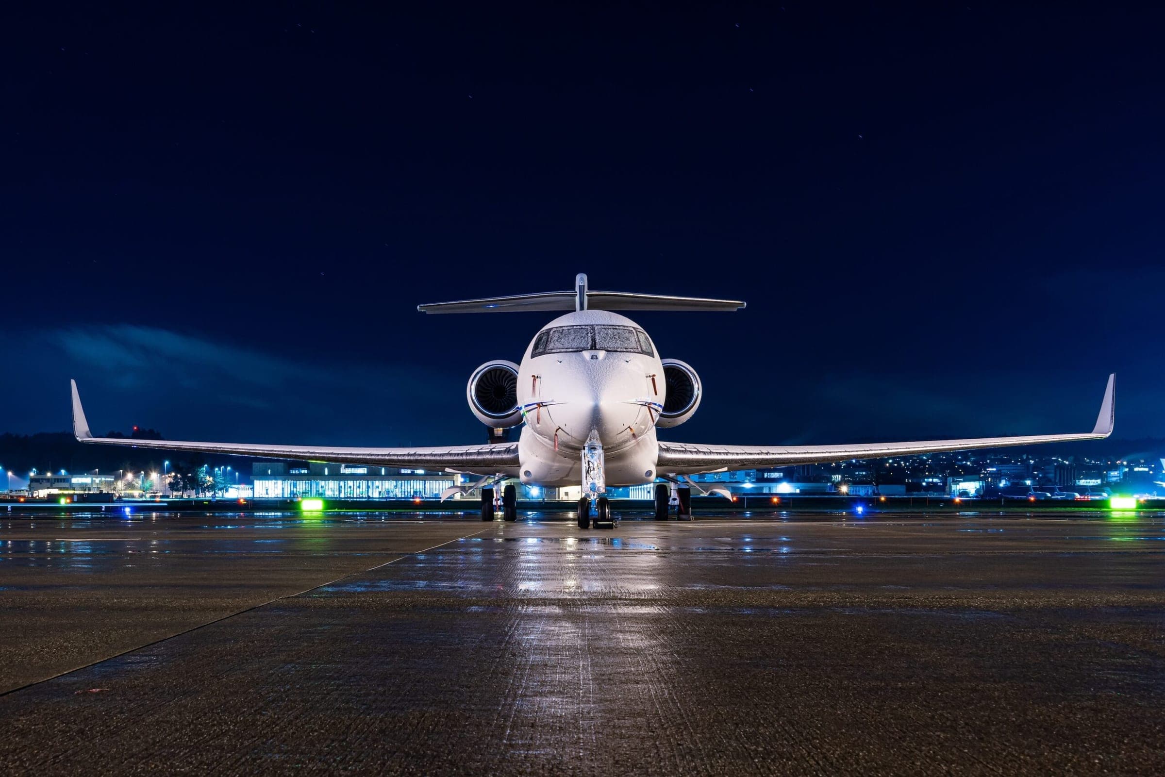 White private jet parked at airport during night time with snow on the cockpit window