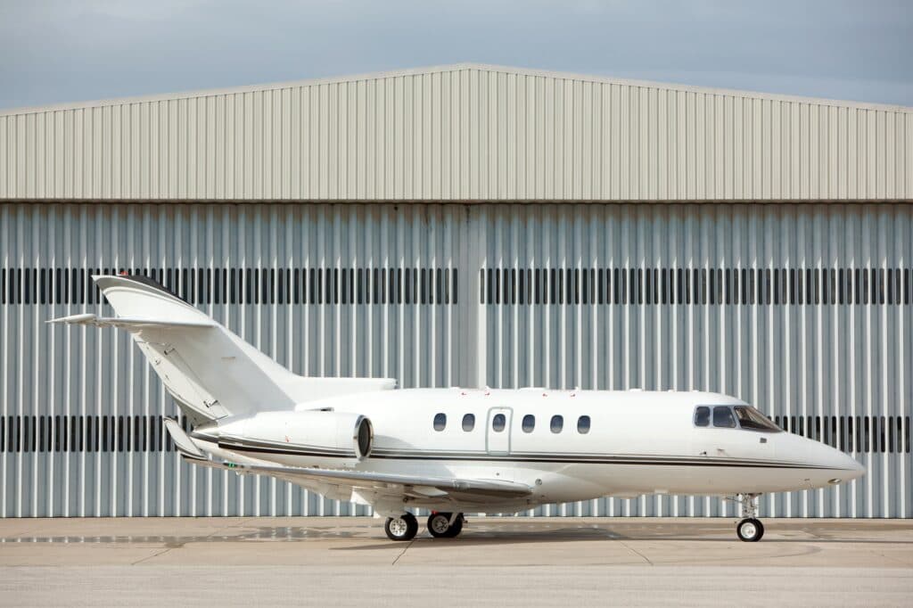 White Hawker 800XP on ground in front of hangar side on view