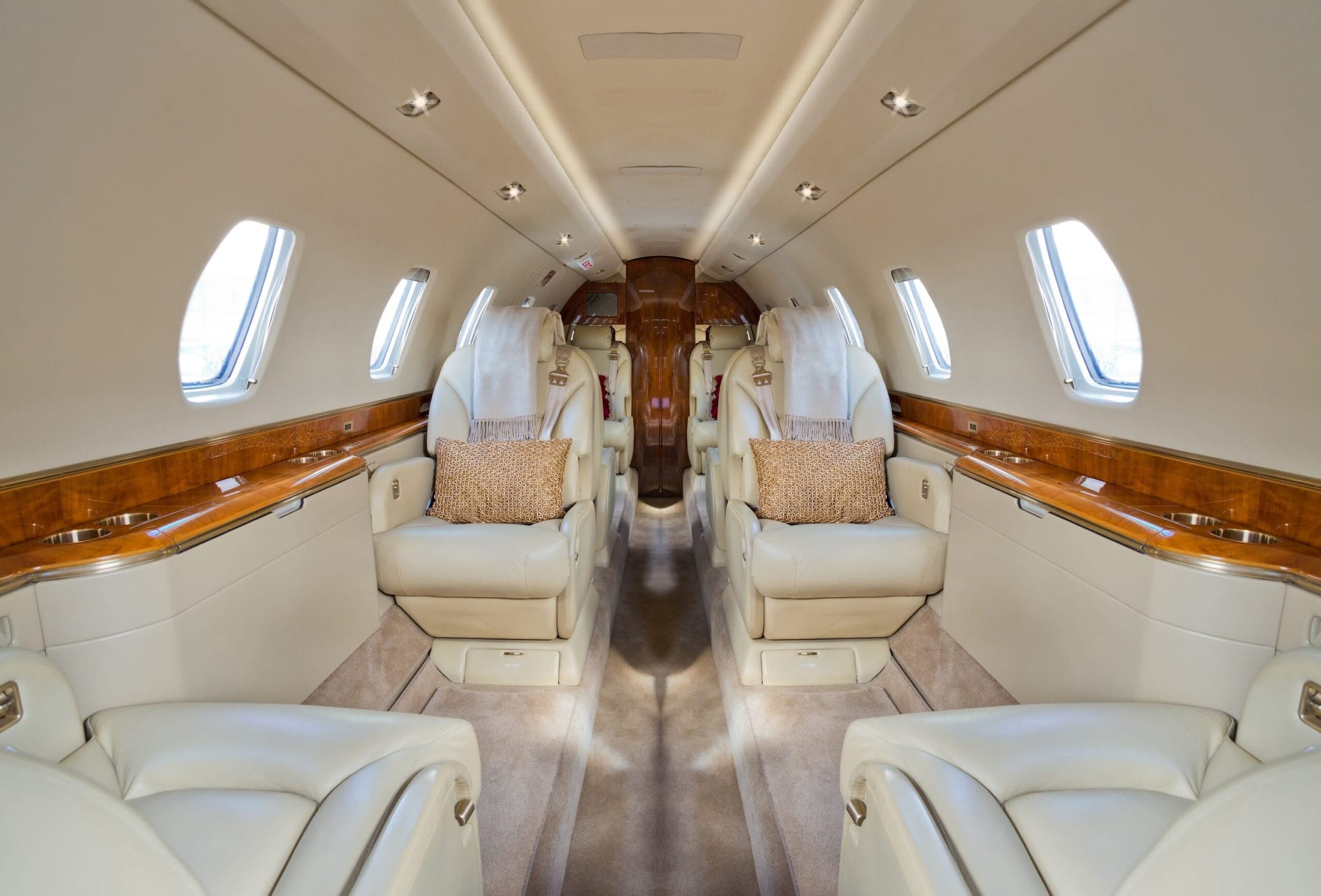 Interior of private jet from front of cabin looking back with cushions