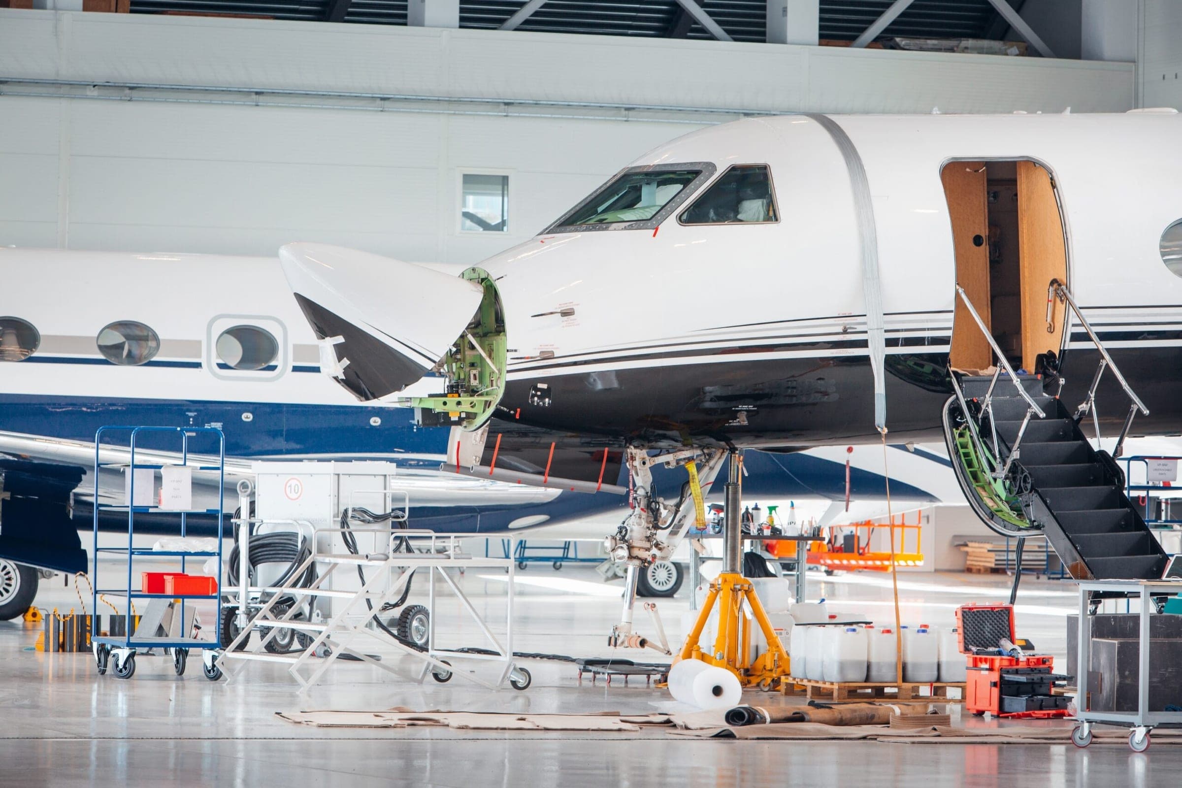 Maintenance hangar of private jets with nose of aircraft raised to reveal internal components