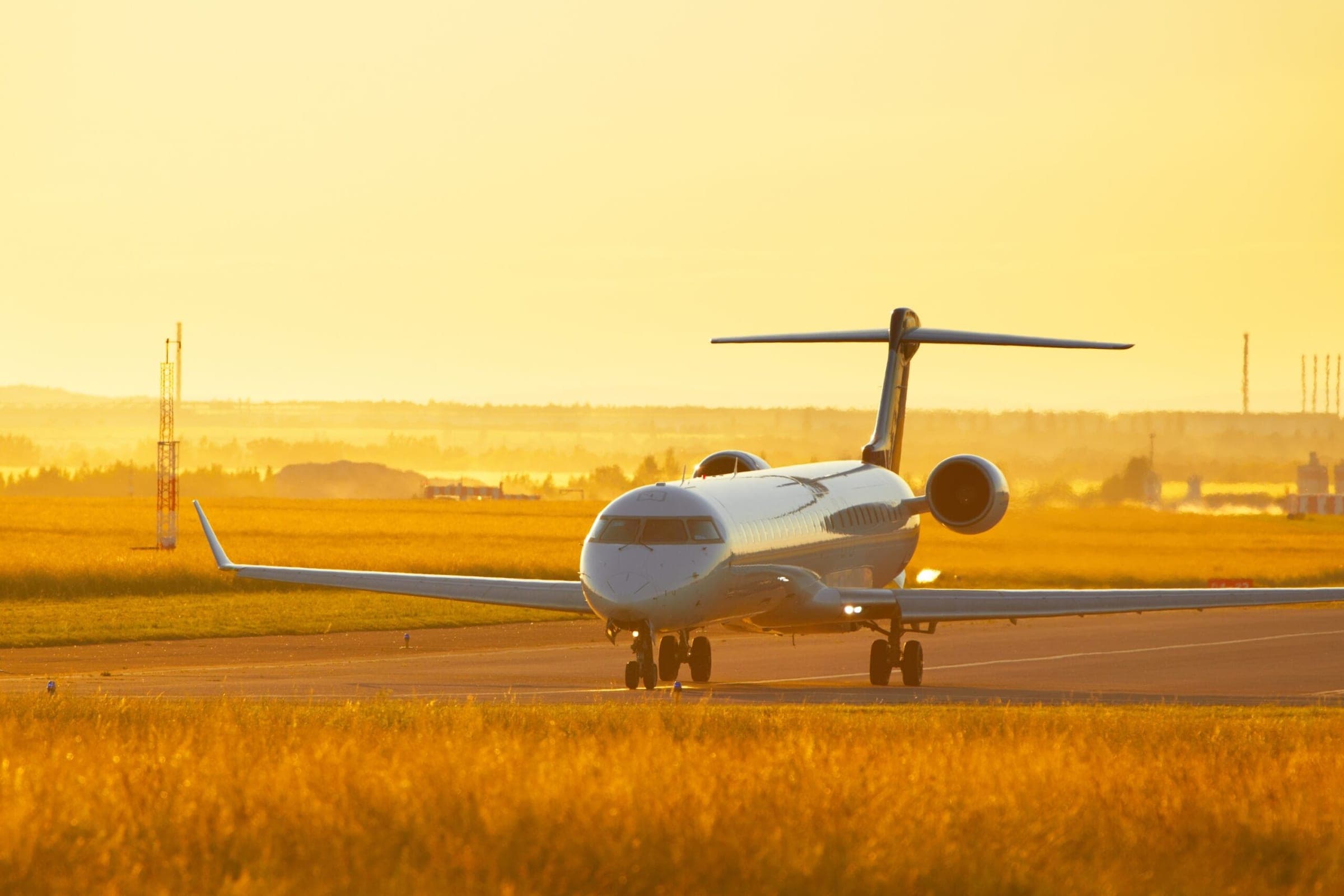 Large private jet taxiing at airport during sunset, golden sky