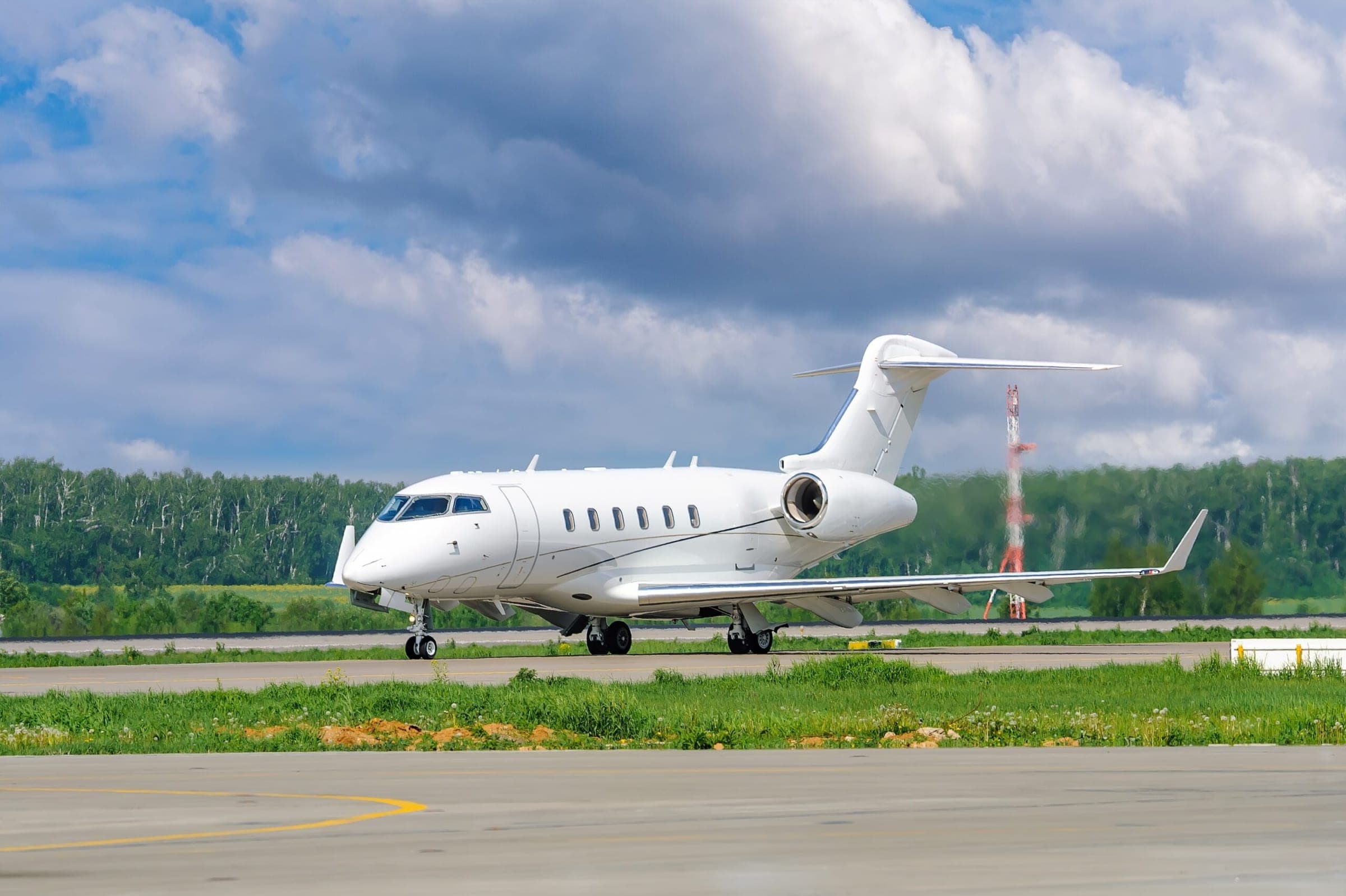 A private white business jet on the runway is preparing for takeoff. Jets of hot exhaust come from jet engines