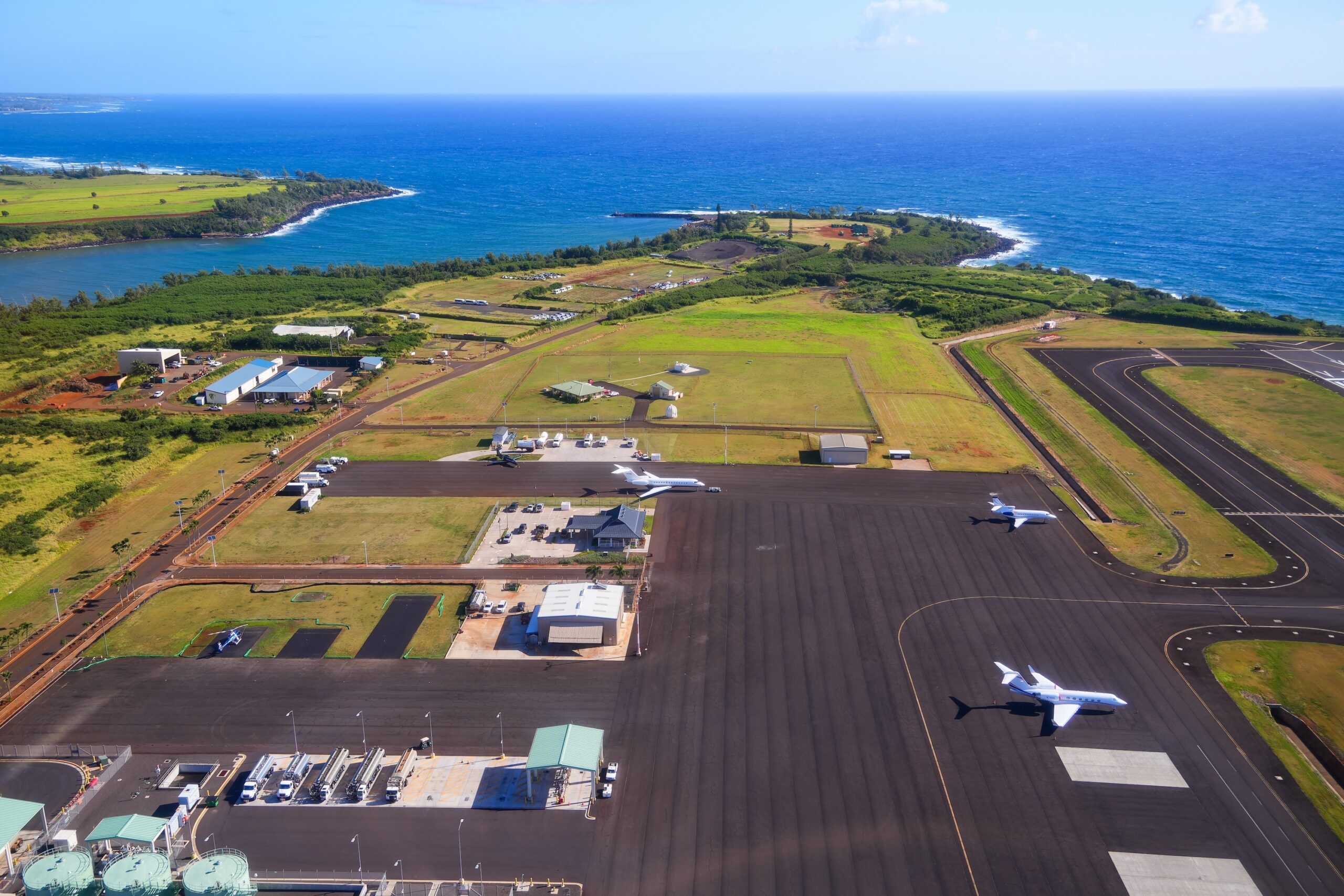Aerial view of the runway and plane hangars of Lihue airport on Kauai island, Hawaii, United States, with private jets parked on the apron