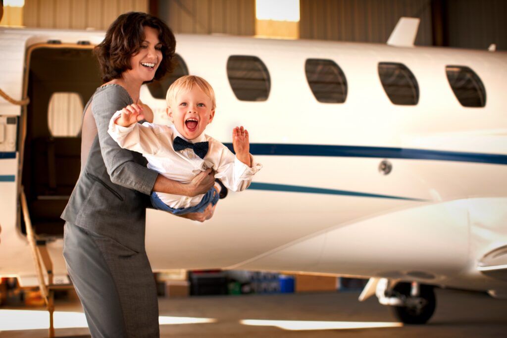 Woman lifting baby in the air in front of private jet