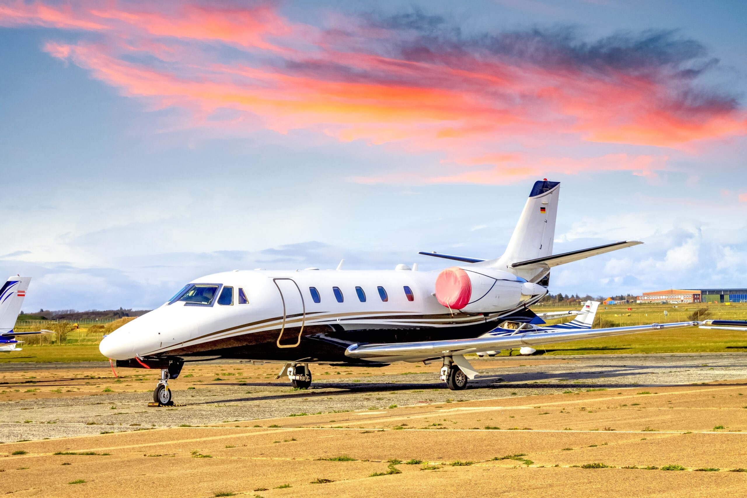 Cessna Citation with engine covers on parked at airport Sylt, Germany, with orange sky above