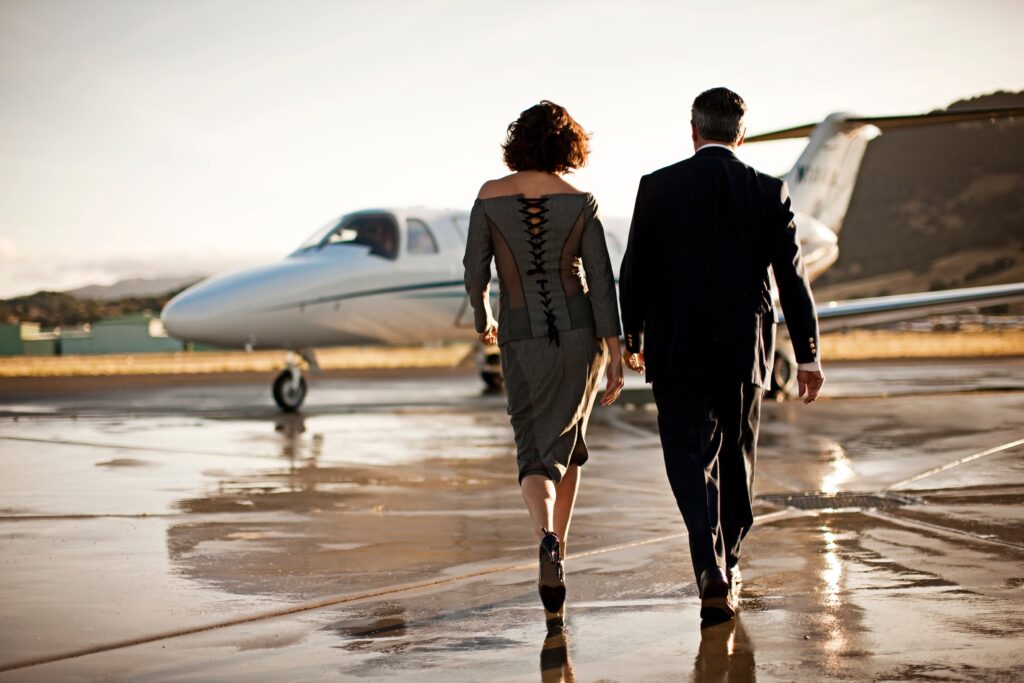 Well-dressed couple walking towards a private jet over wet apron