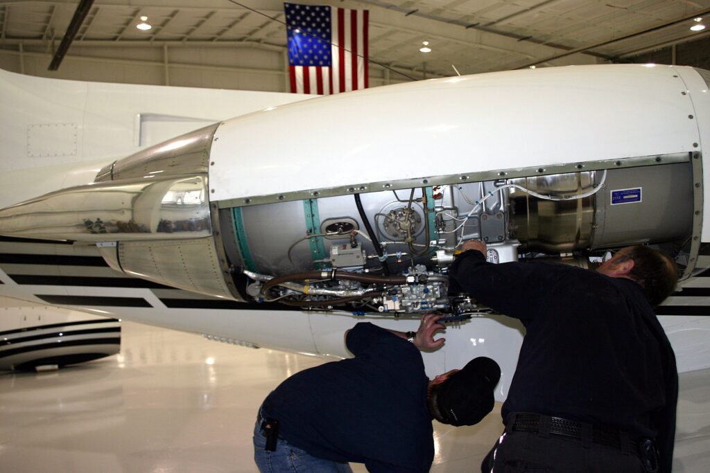 Two men performing maintenance on jet engine