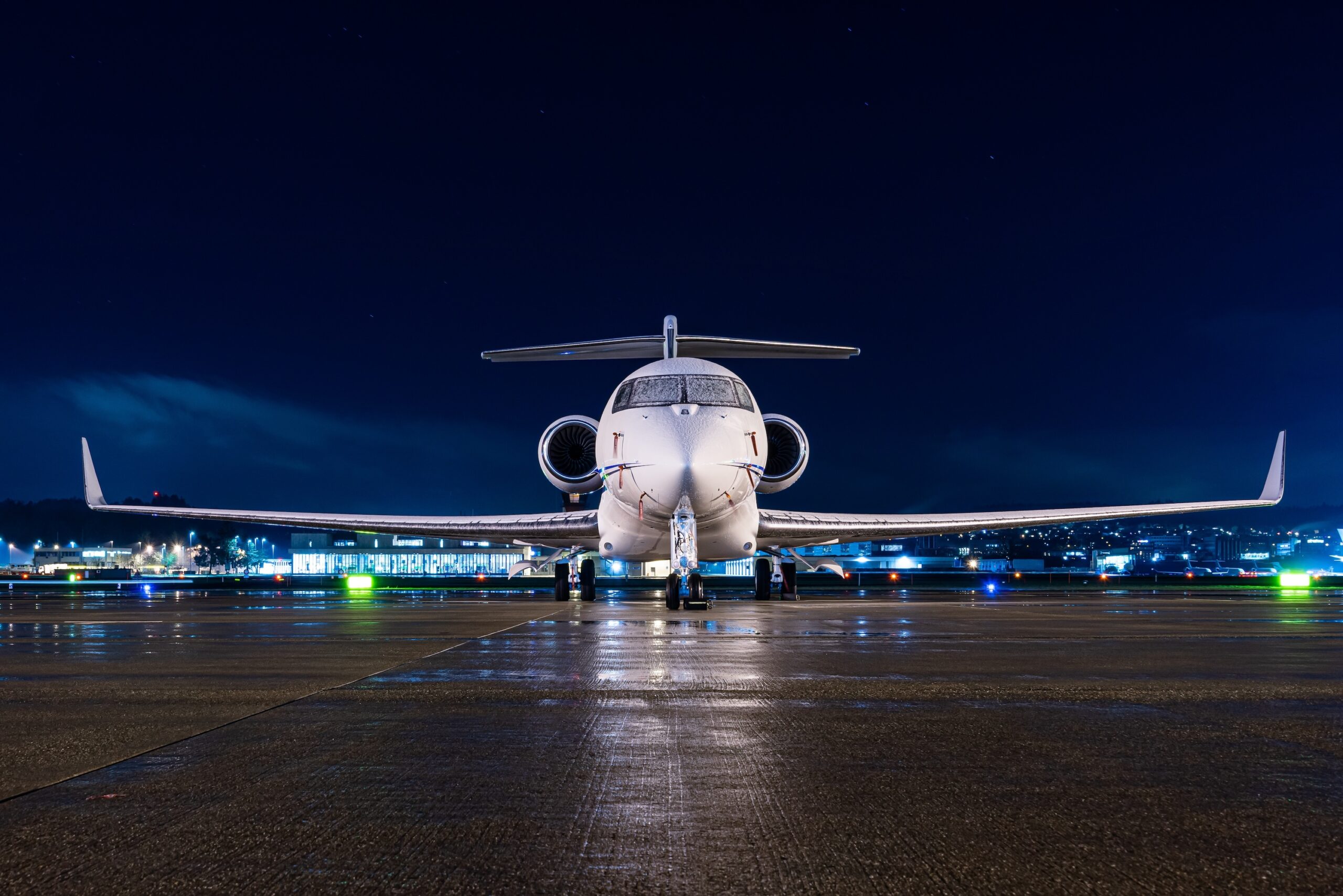 White private jet parked at airport during night time with snow on the cockpit window