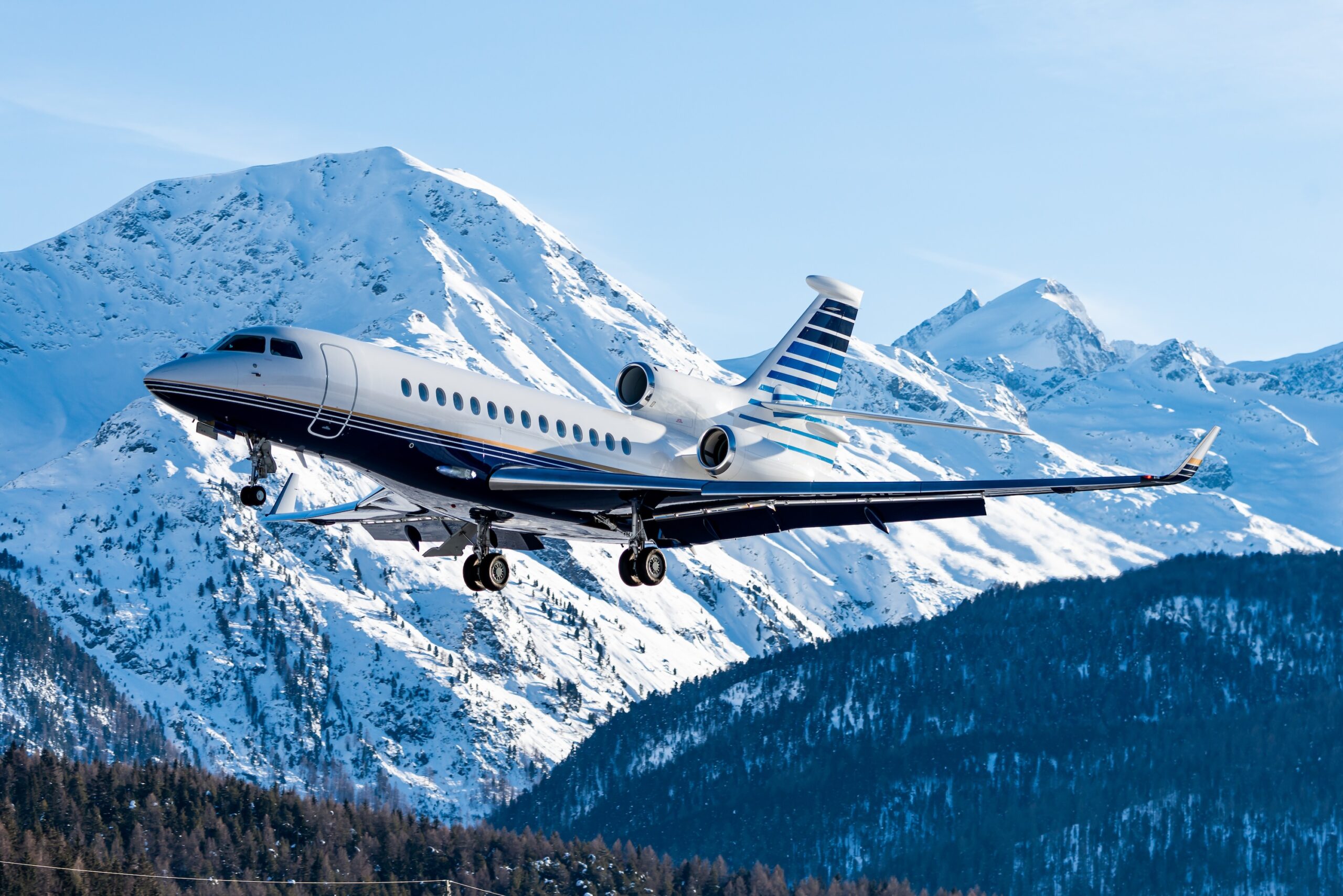 Dassault Falcon tri jet aircraft landing at an alpine airport with mountains in the background