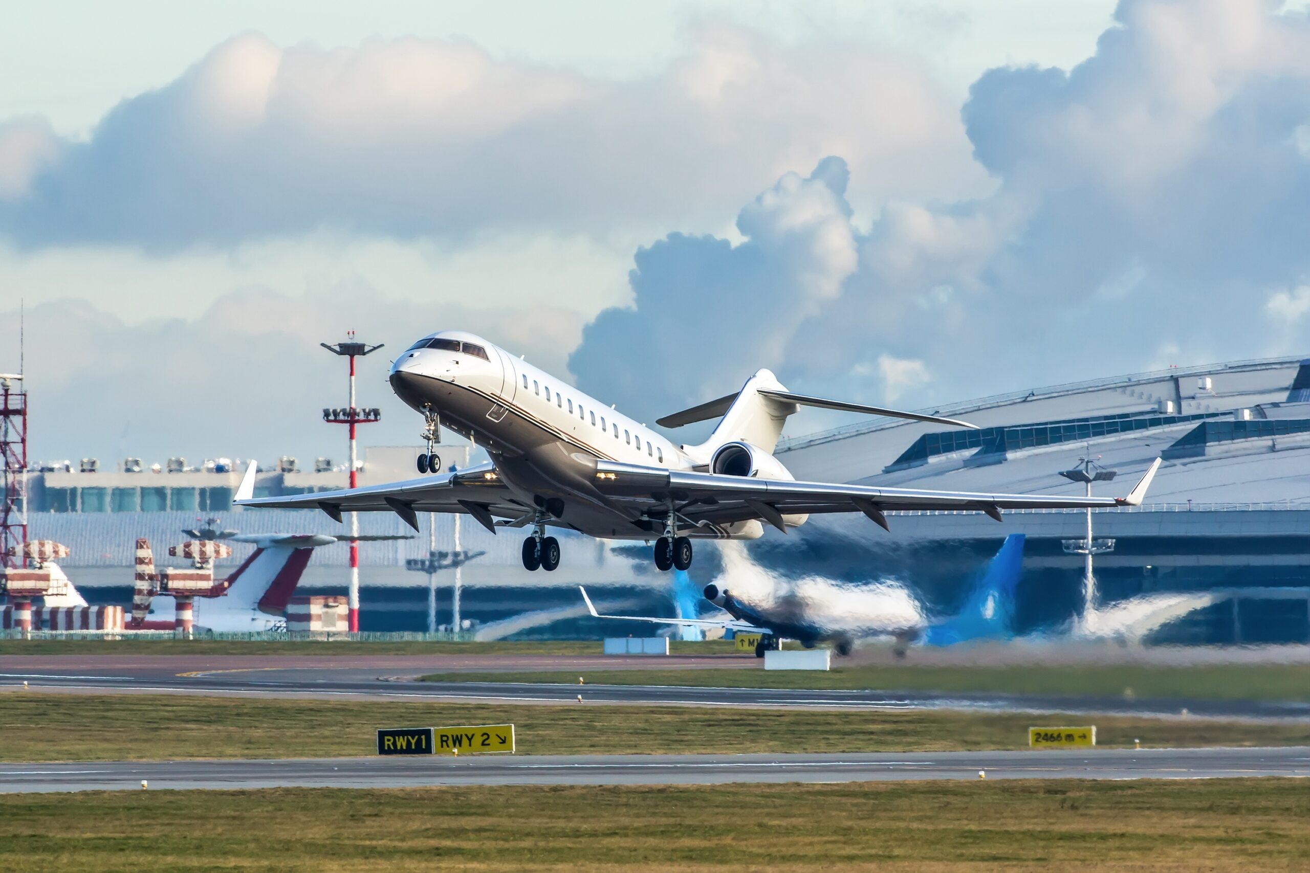 Bombardier Global private jet taking off from airport with jet exhaust visible behind