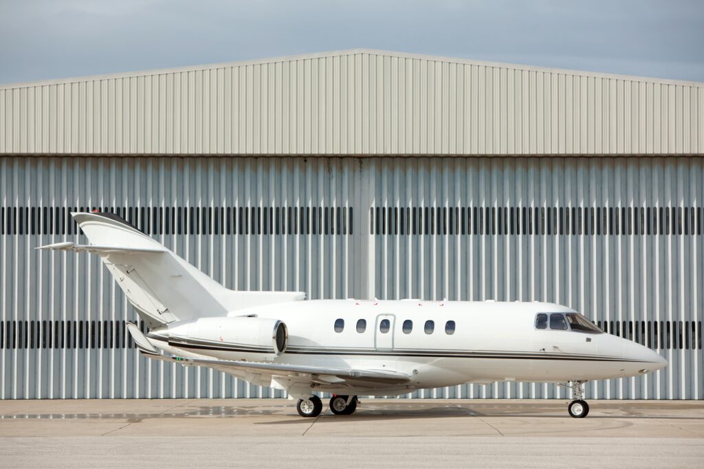 White Hawker 800XP on ground in front of hangar side on view