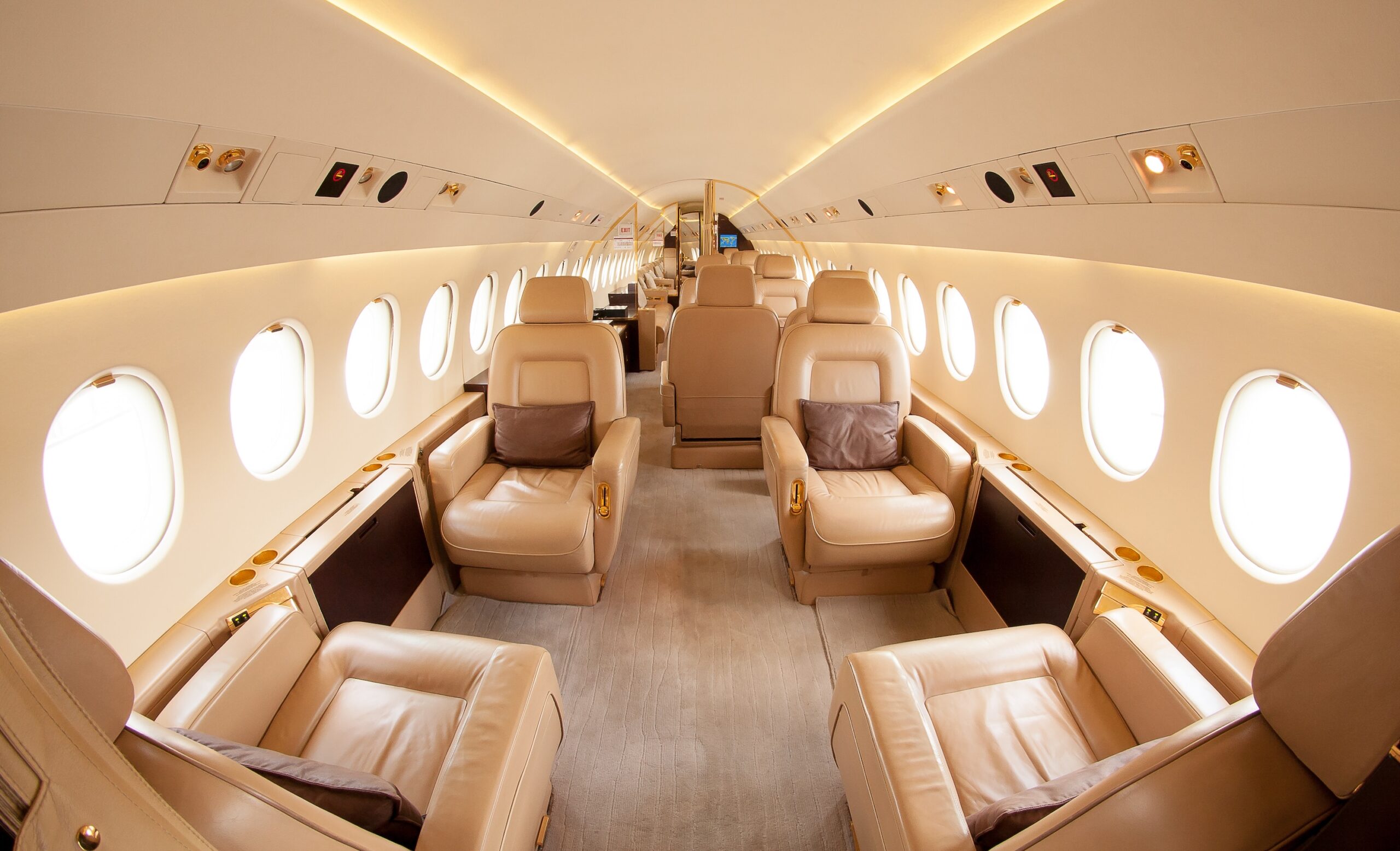 Interior of private jet with beige leather seats looking to rear of aircraft from front of cabin