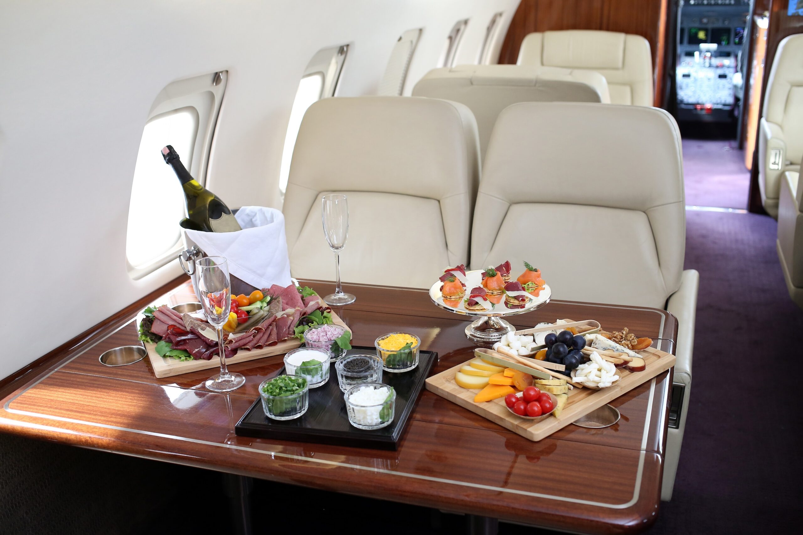 Selection of food and champagne on table in private jet - private jet vs first class
