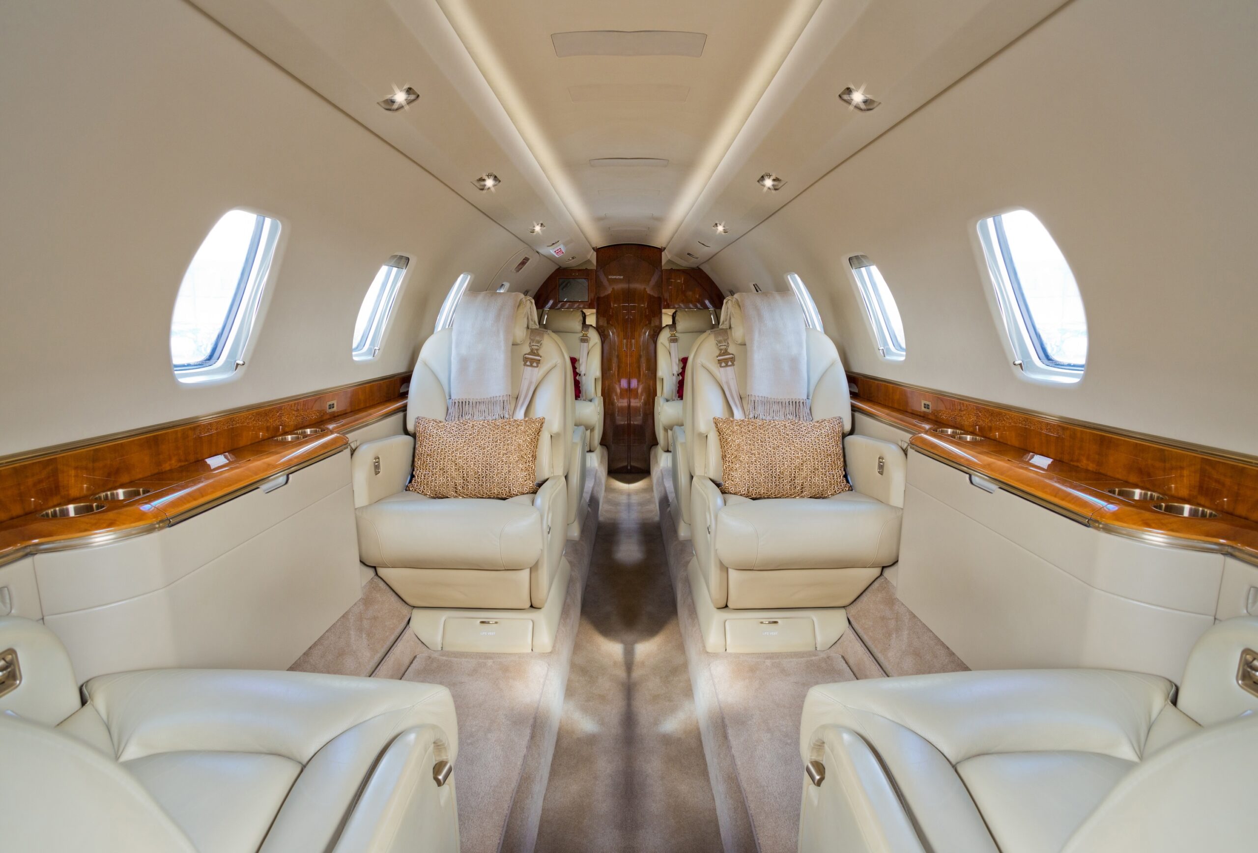 Interior of private jet from front of cabin looking back with cushions