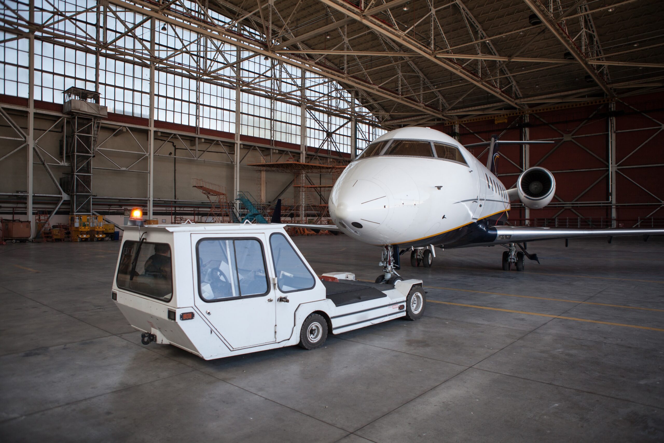 Private jet attached to tug in hangar