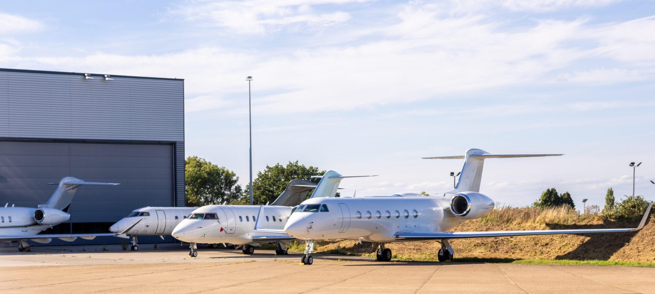3 private jets lined up at airport parking all white