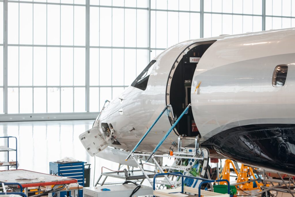 Maintenance of Embraer Legacy in hangar with stairs disassembled and hatch at front open