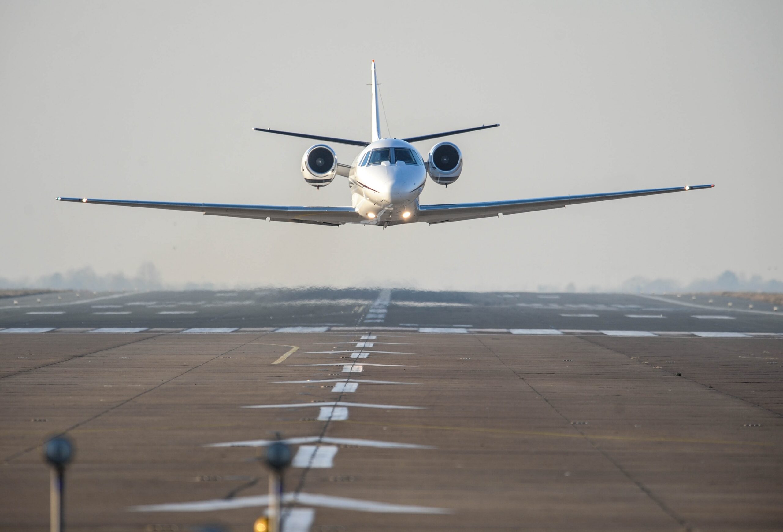 Business private jet in low level flight over runway