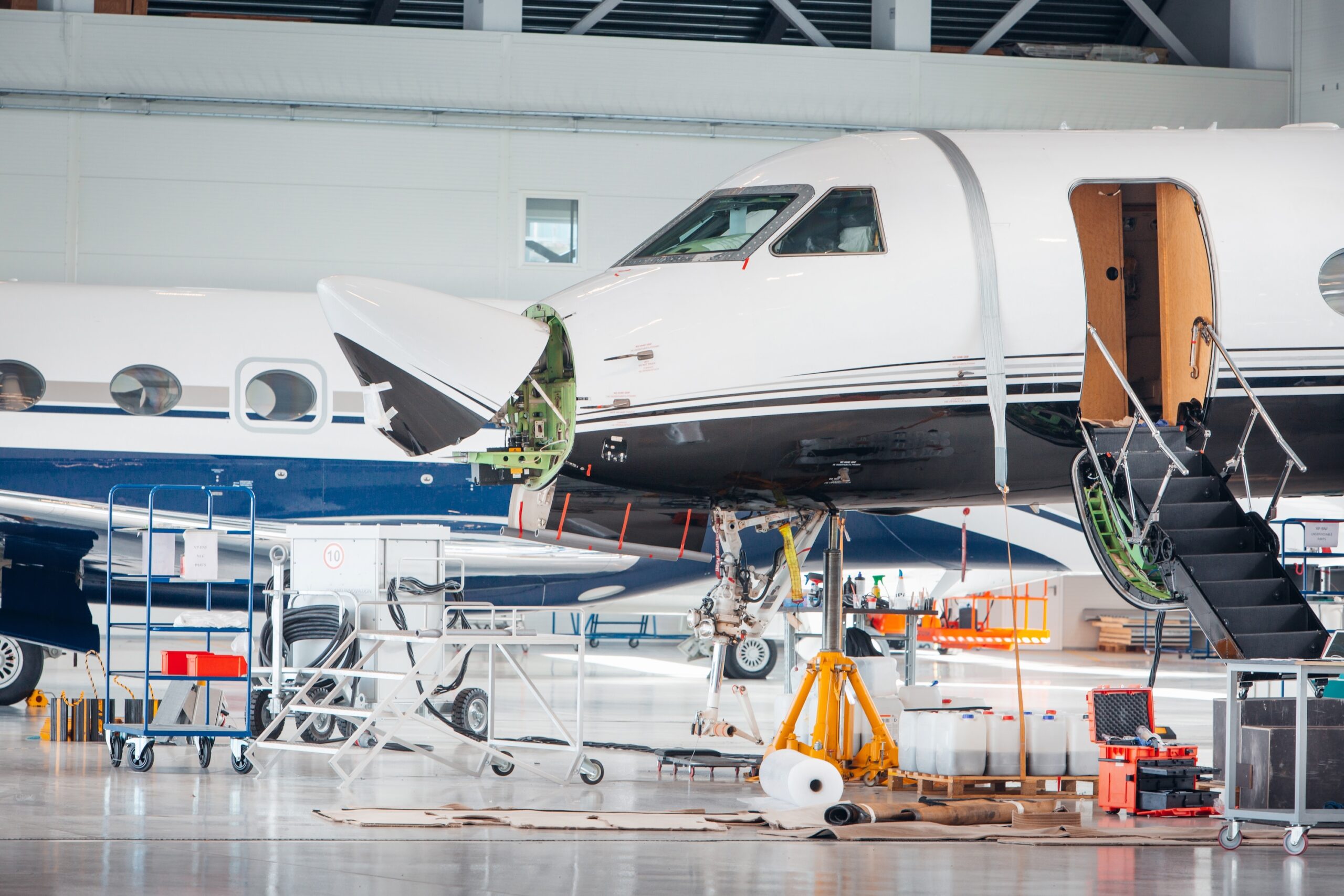 Maintenance hangar of private jets with nose of aircraft raised to reveal internal components