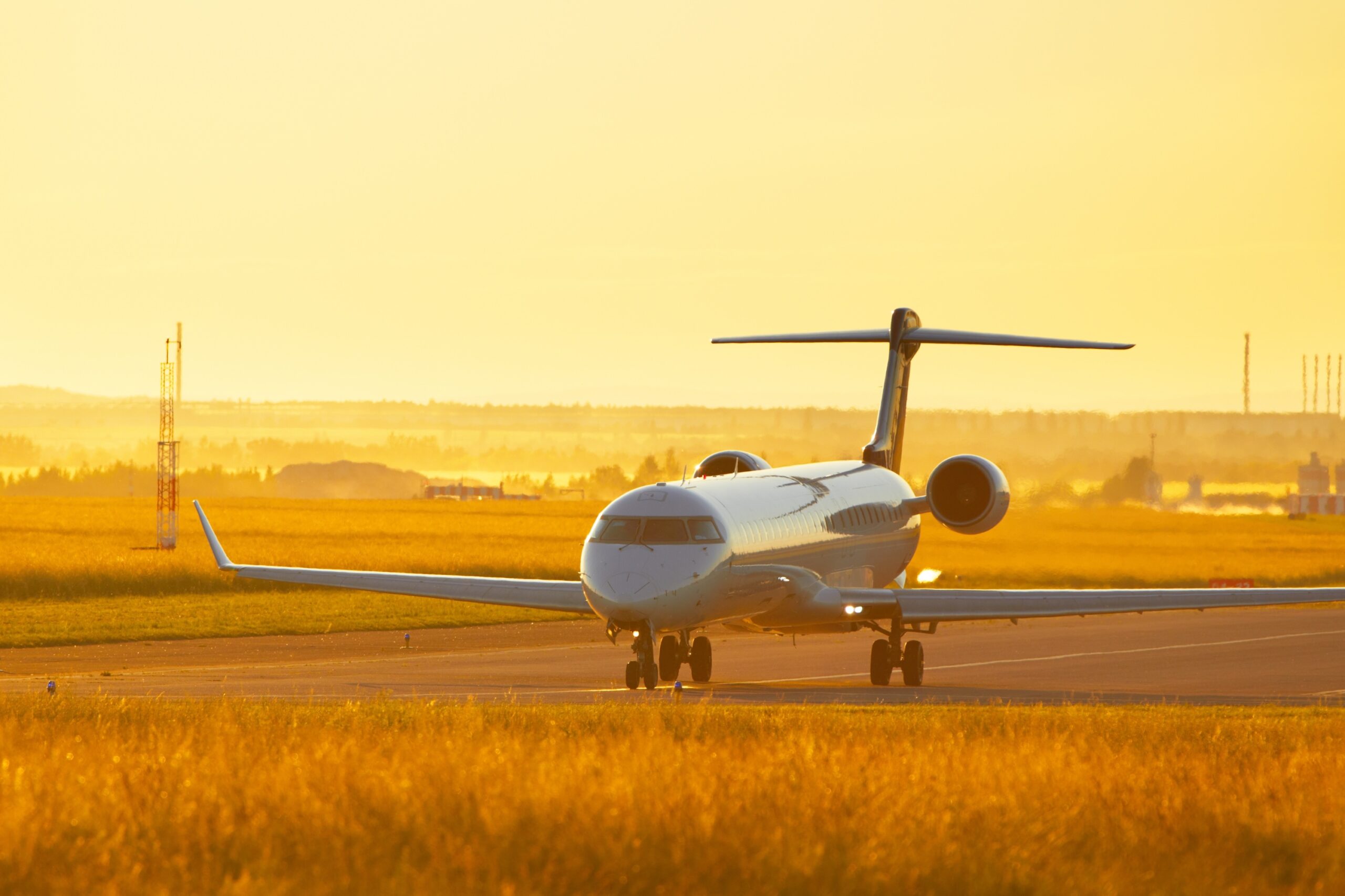 Large private jet taxiing at airport during sunset, golden sky
