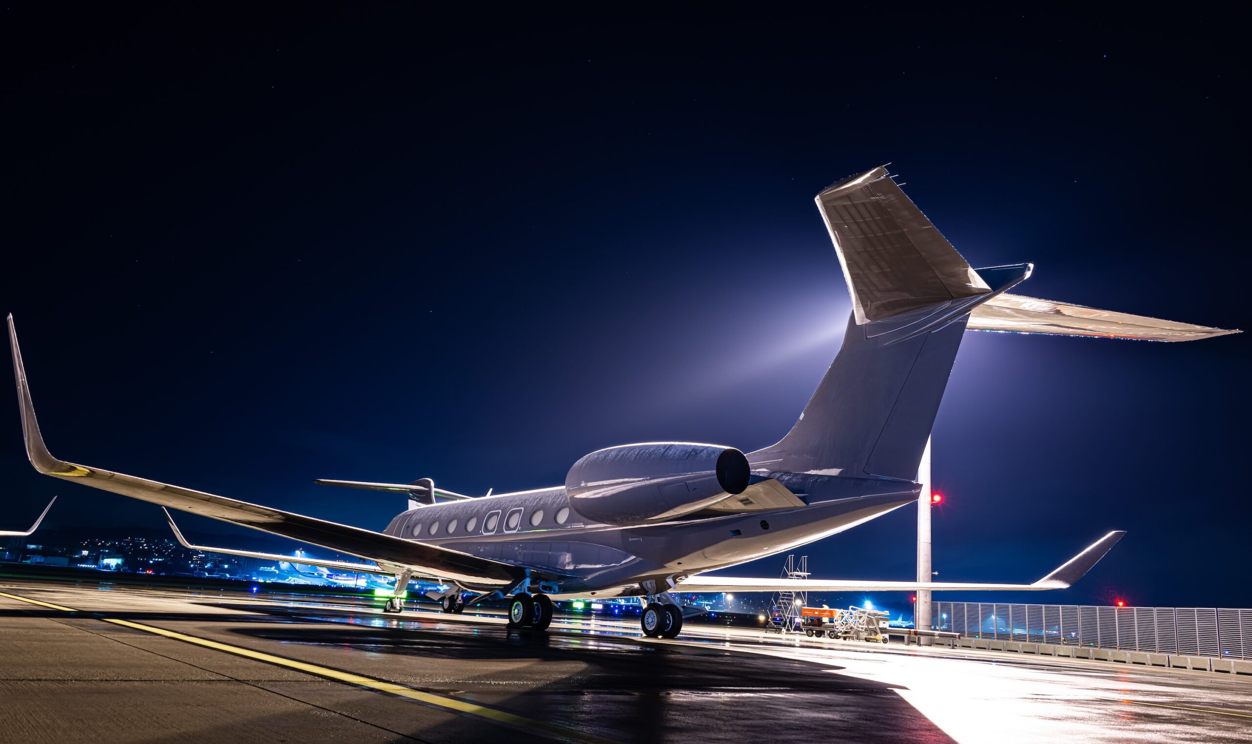 Gulfstream with dark paint at airport during night with light behind it