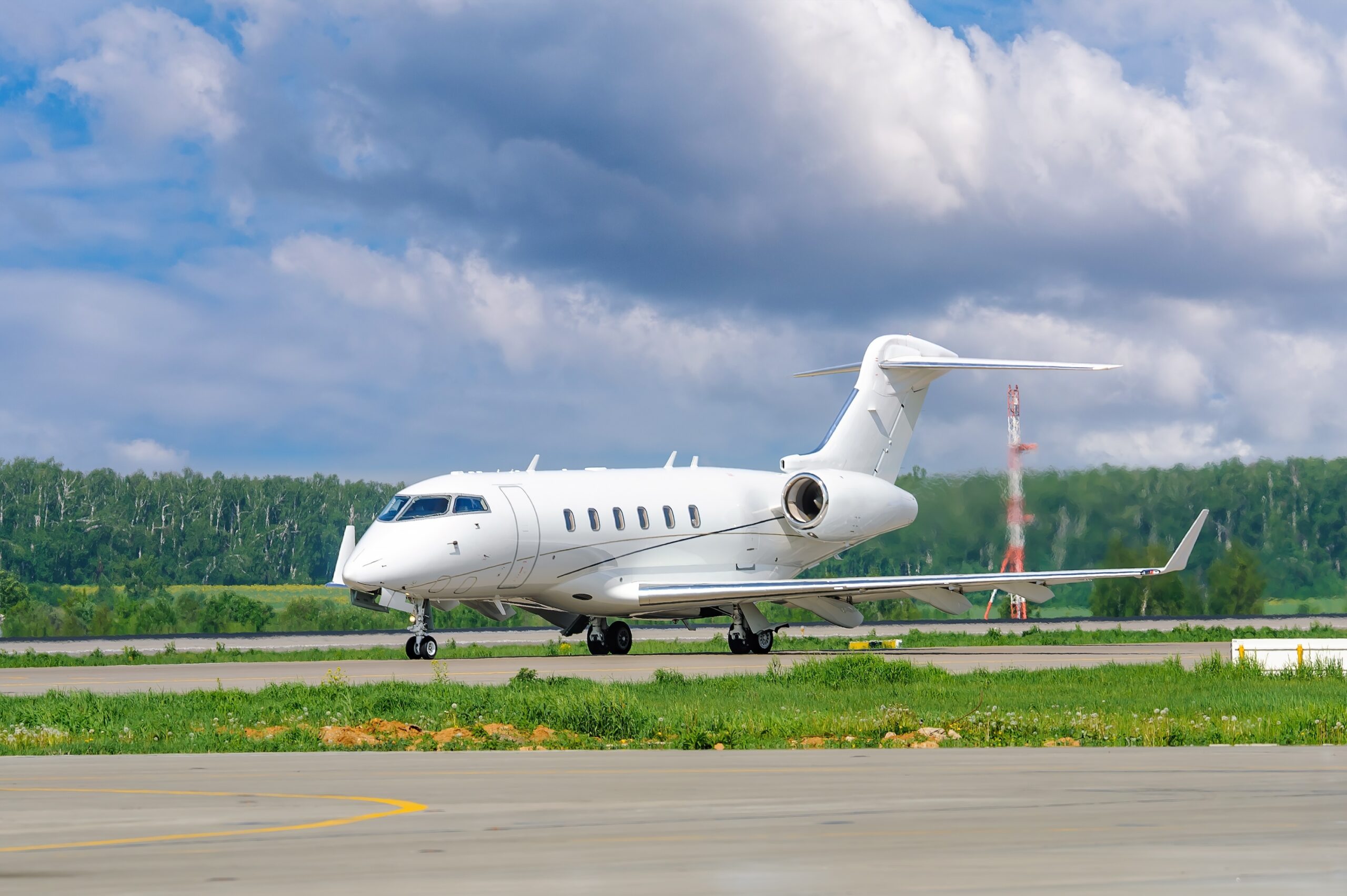 A private white business jet on the runway is preparing for takeoff. Jets of hot exhaust come from jet engines