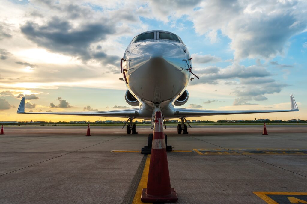 low angle shot of private jet at airport nose on with cone in front and sunset in the background, symbolizing the fixed costs involved with aircraft ownership
