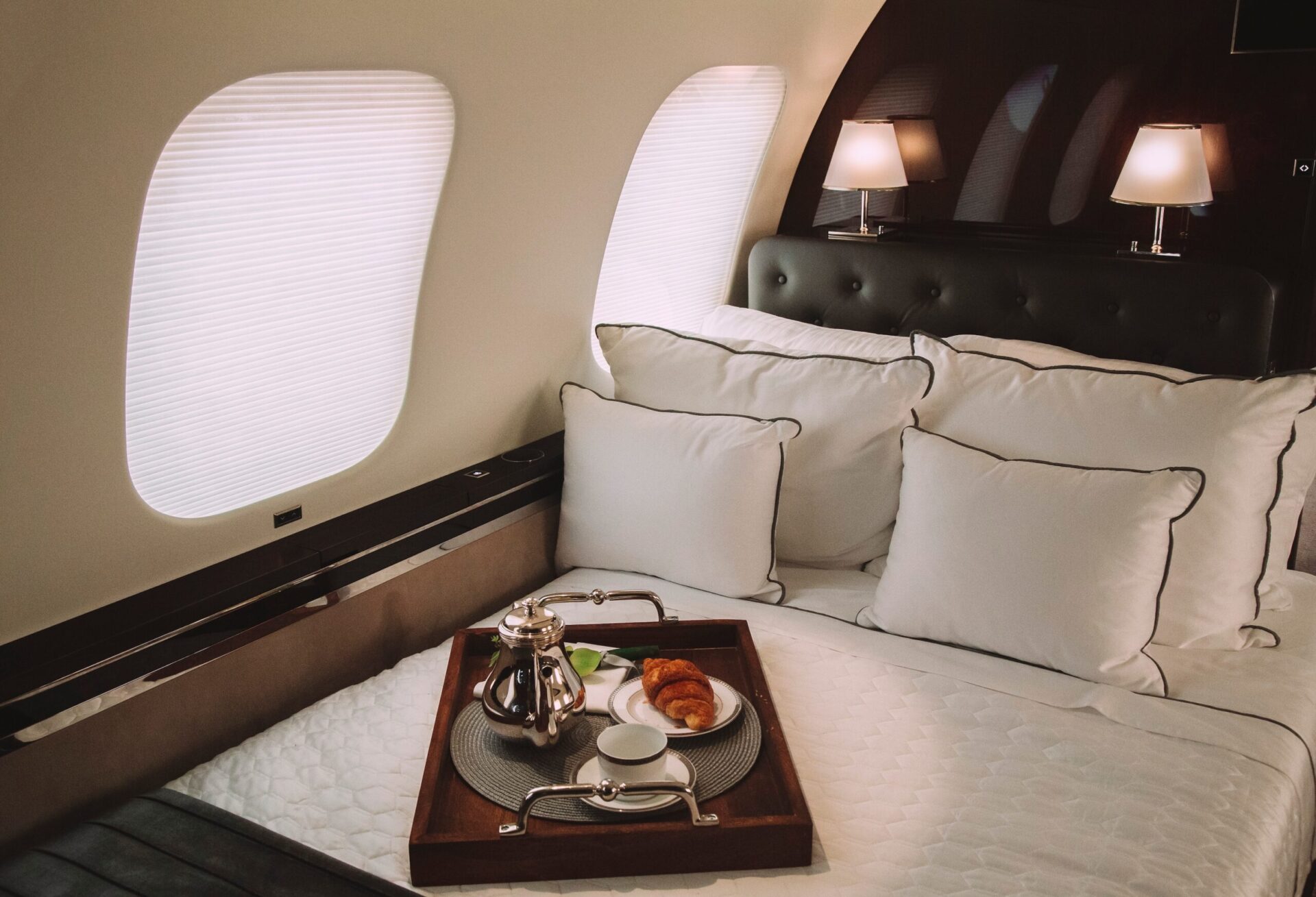 Bed in private jet with breakfast on the bed on tray