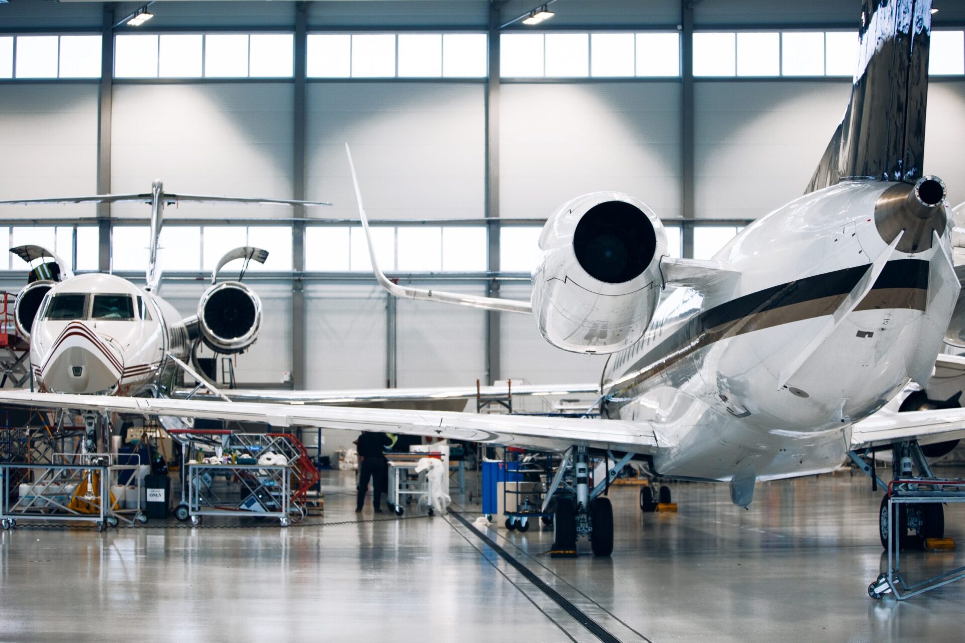 Maintenance of airplane in large white hangar. Modern private jet at the factory