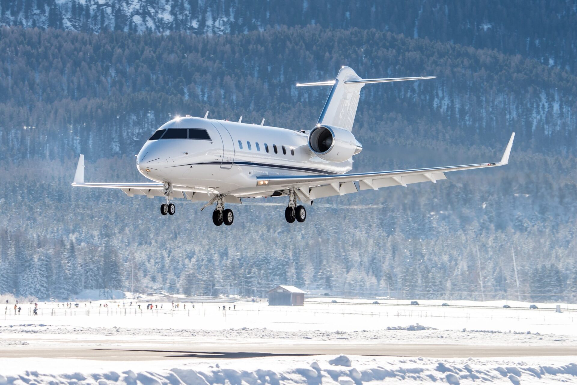 White Bombardier Challenger 605 on final to land at snowy airport