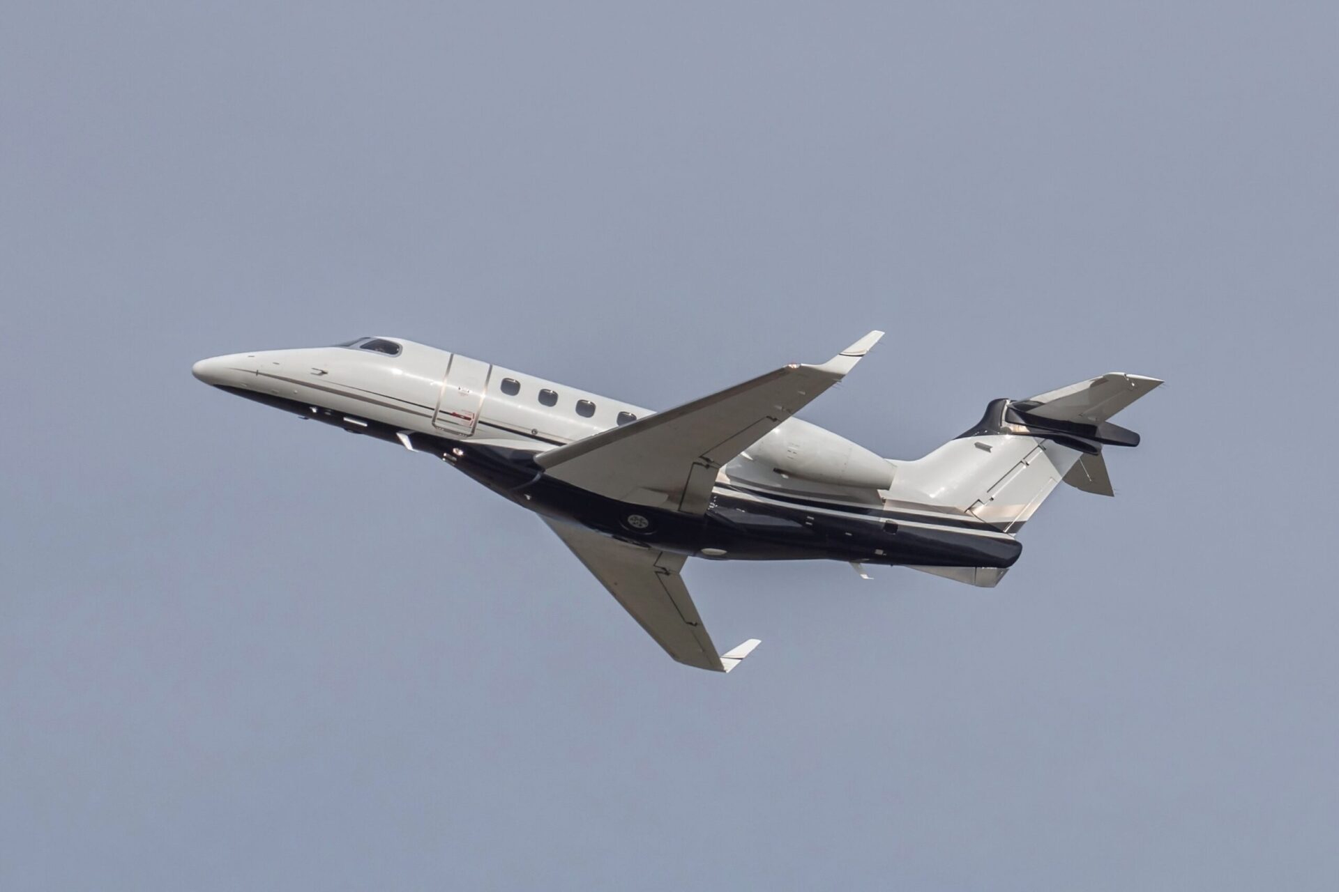 Side view of Embraer Phenom 300 taking off from airport
