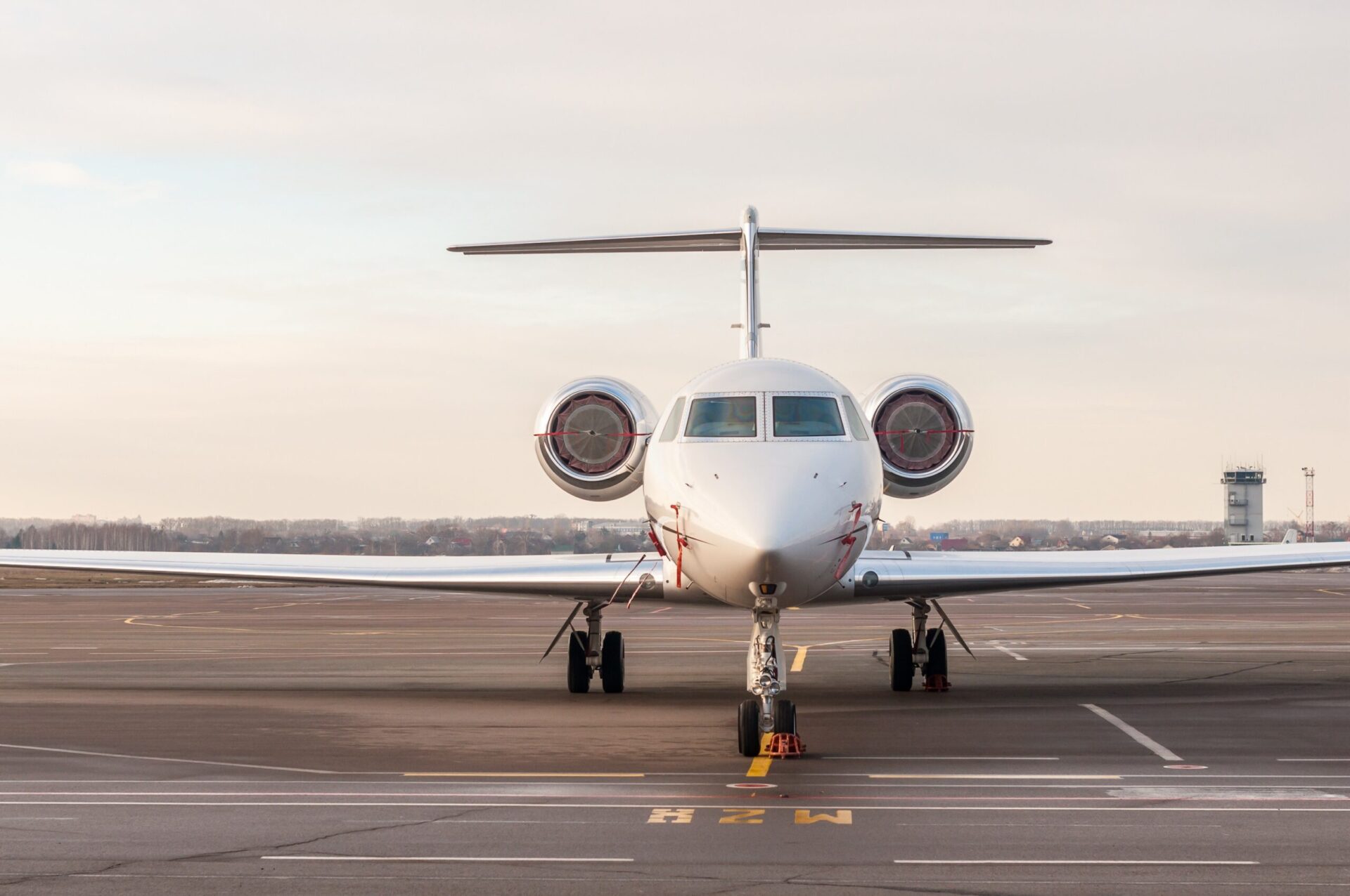 front view of private jet parked at airport with engine covers