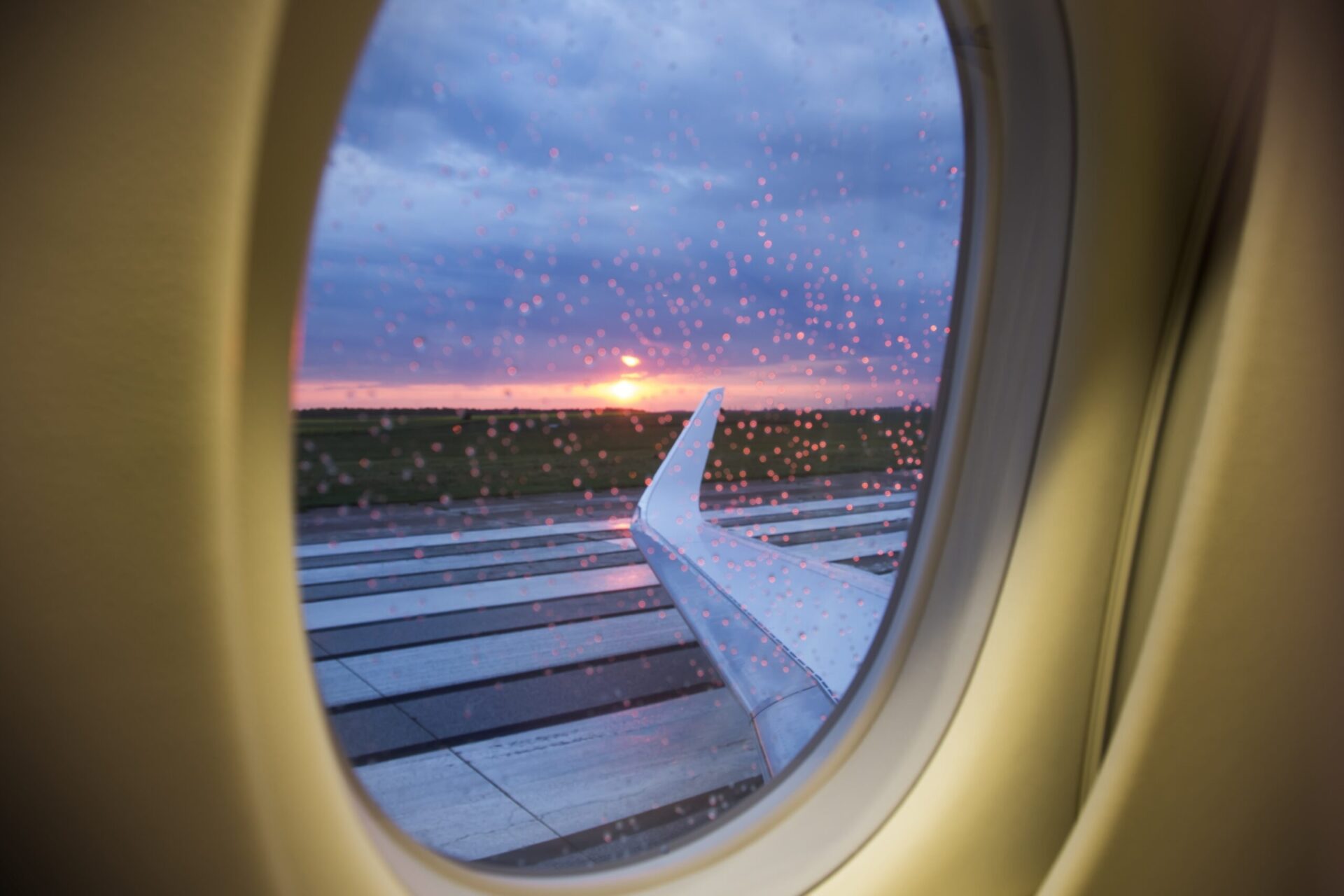 View out business jet window over wing at sunrise