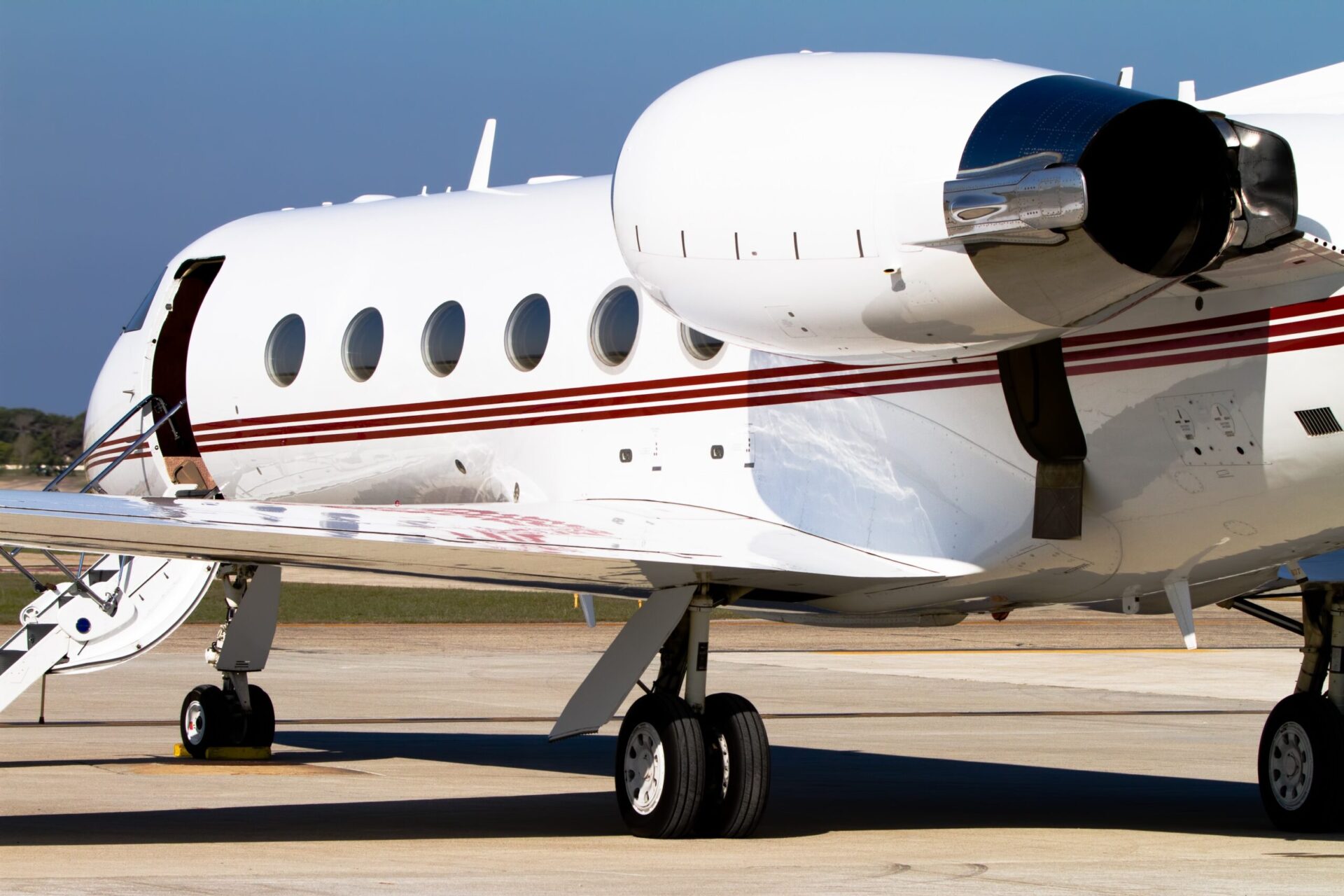 Rear quarter view of Gulfstream private jet parked at airport with stairs deployed