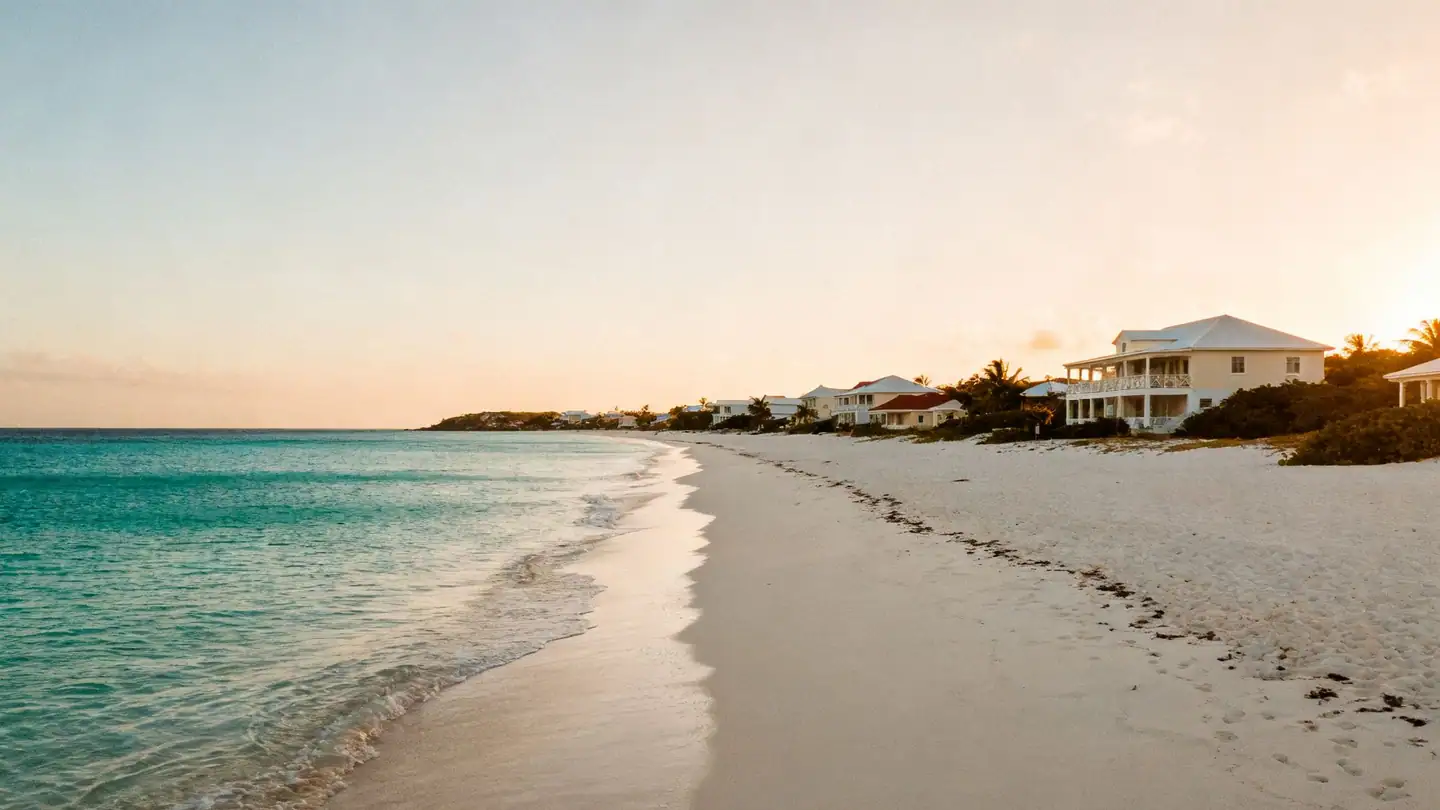 Anguilla: a long flat white-sand beach with very clear turquoise water and low villas in golden-hour light