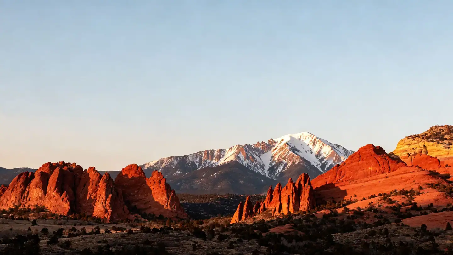 Colorado Springs: red sandstone rock formations with snow-capped Pikes Peak behind in golden-hour light