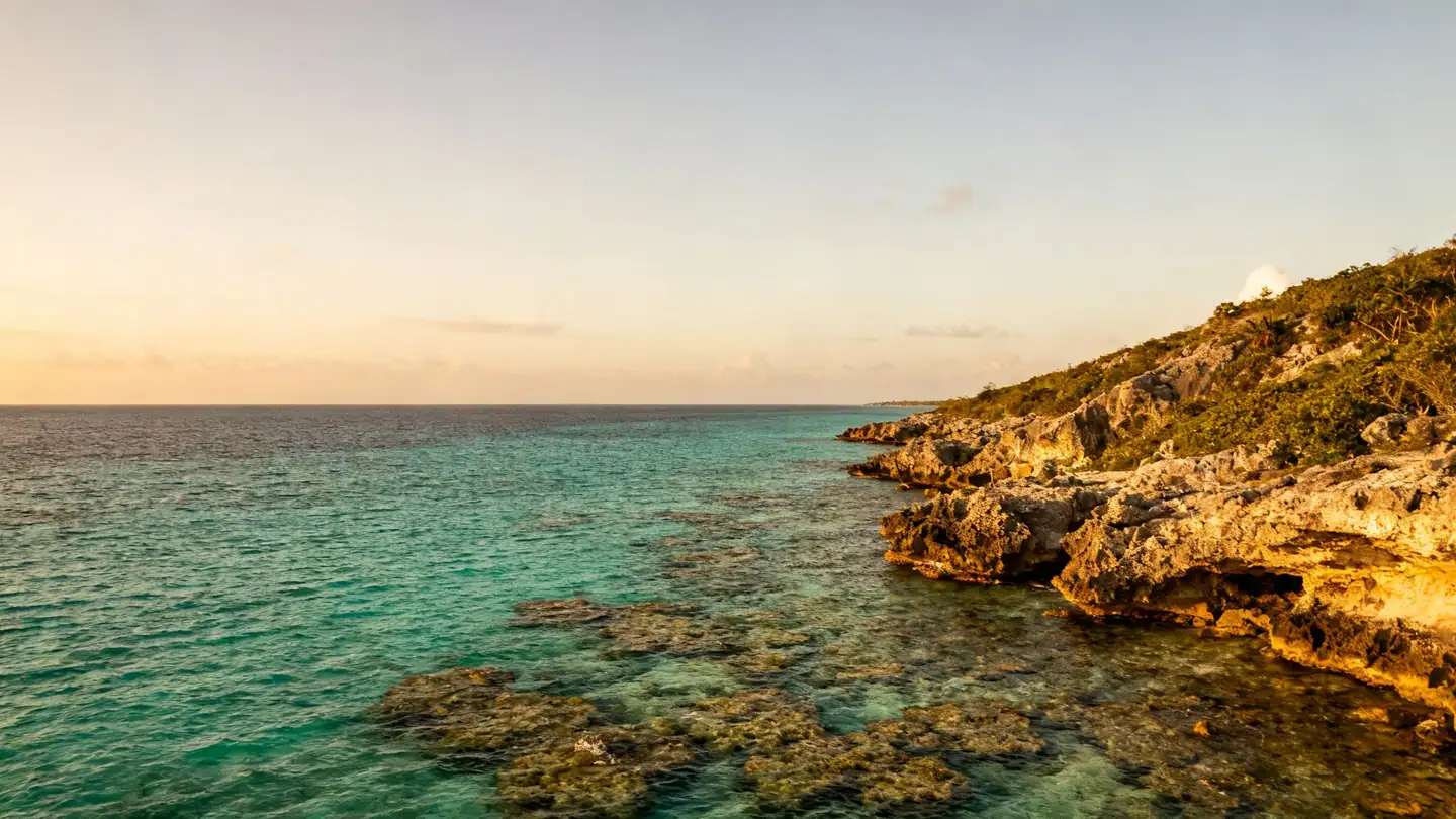Cozumel: clear turquoise Caribbean water over a reef along a rocky coast in golden-hour light