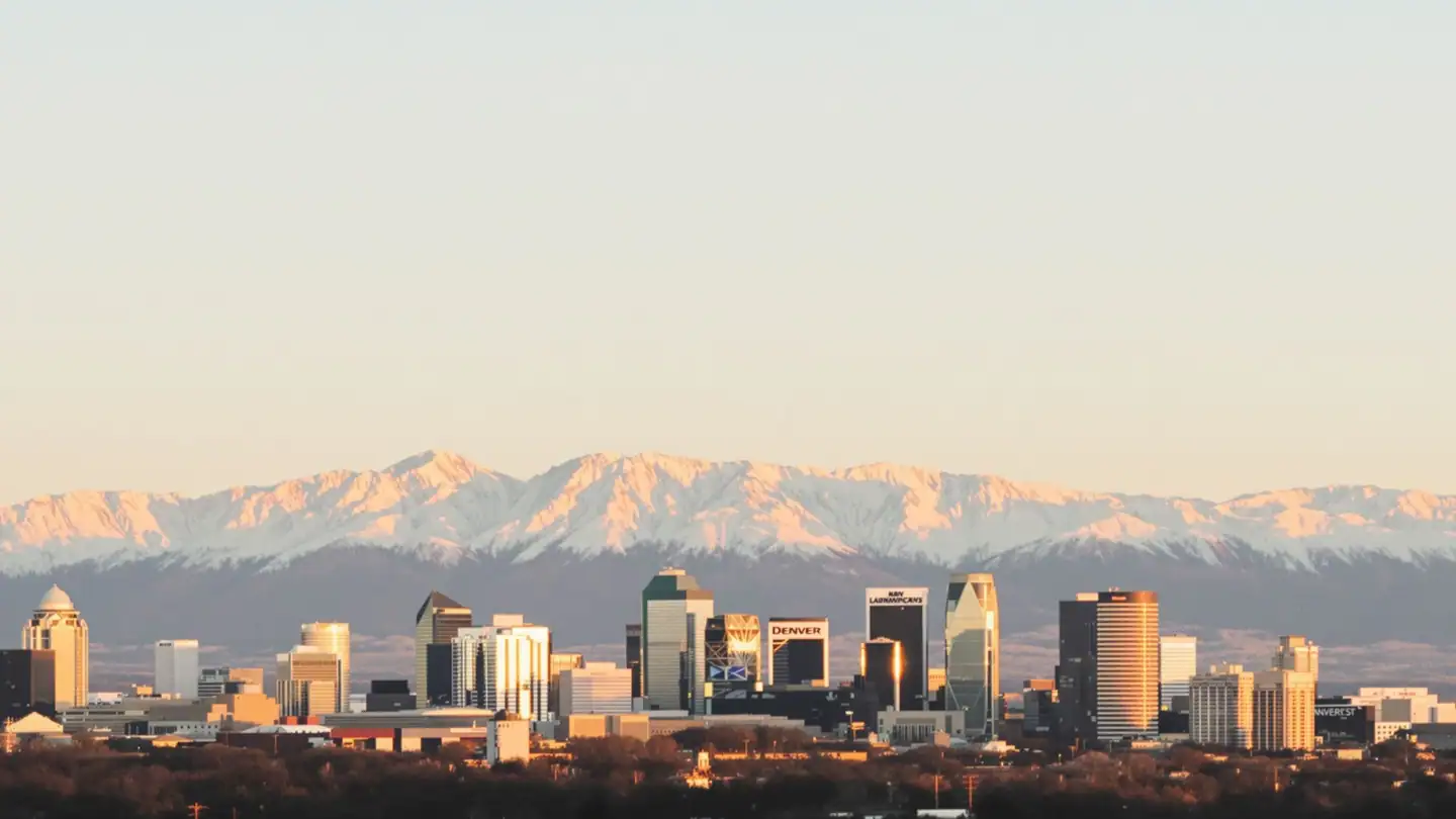 The Denver skyline with the snow-capped Front Range of the Rocky Mountains behind at sunset