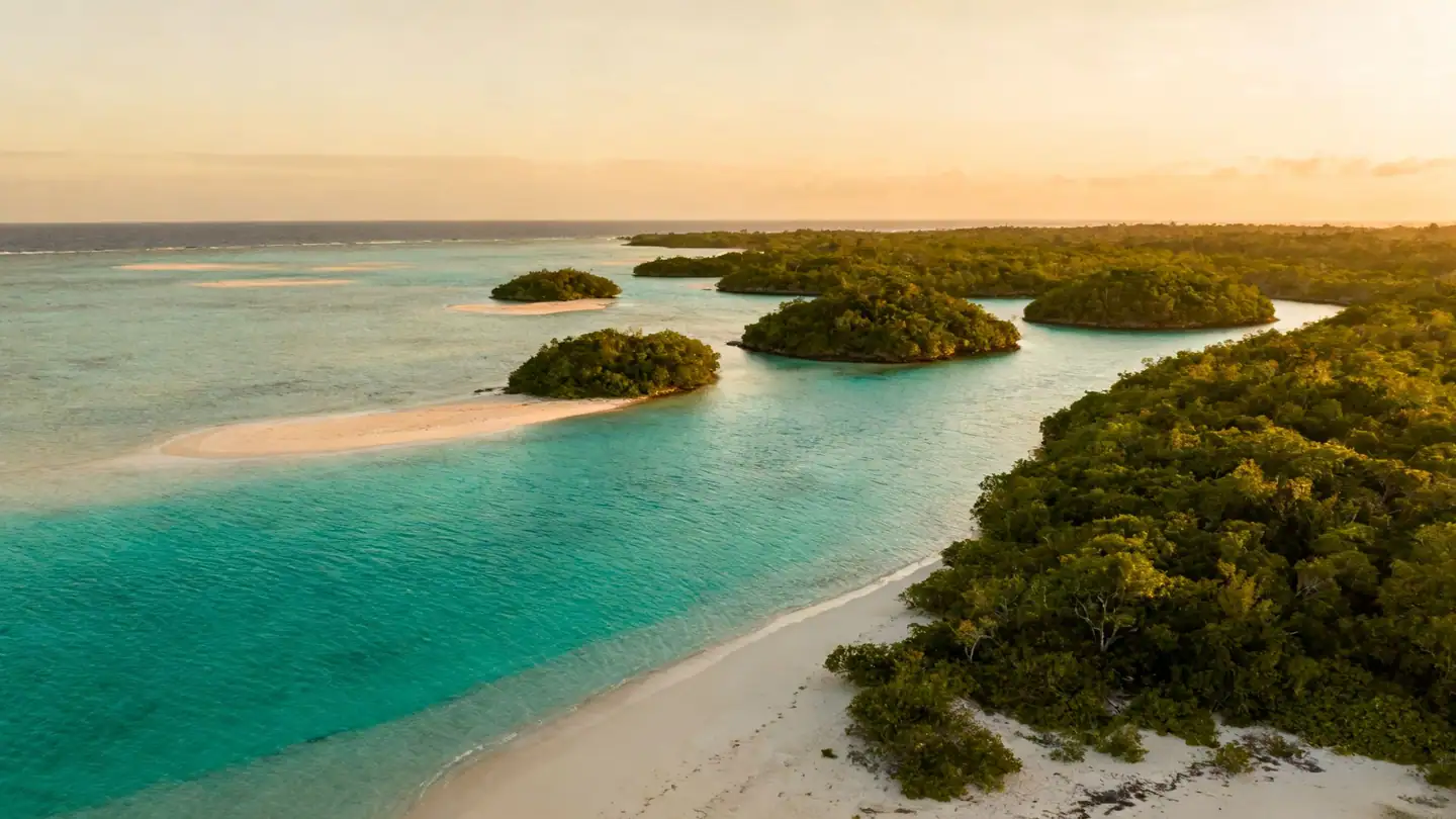 The Exuma Cays: shallow sandbars and electric-turquoise water between small green islands in golden-hour light