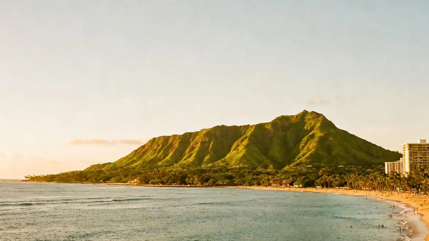 Waikiki beach and the green Diamond Head crater above the Pacific in golden-hour light