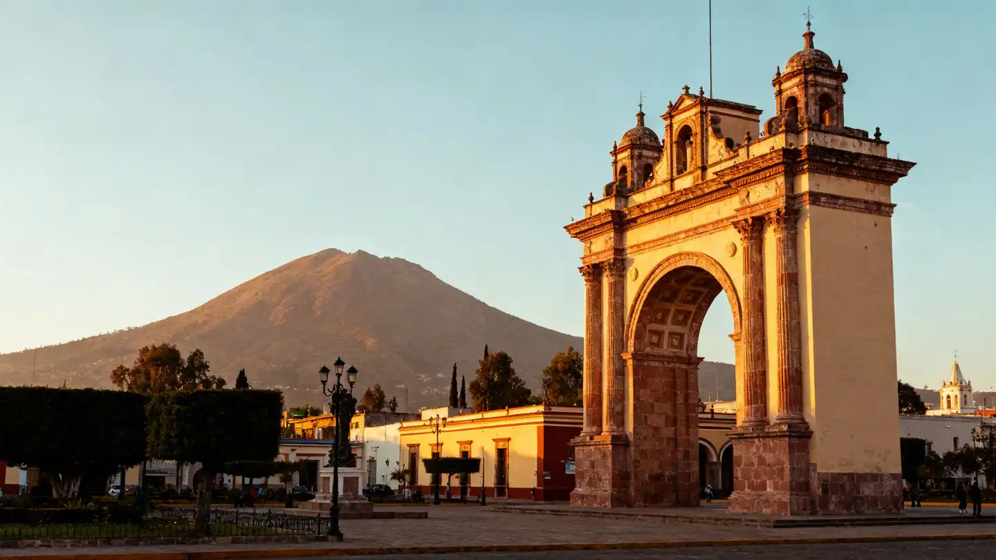 León, Guanajuato: a colonial arch monument and plaza with a mountain backdrop in golden-hour light