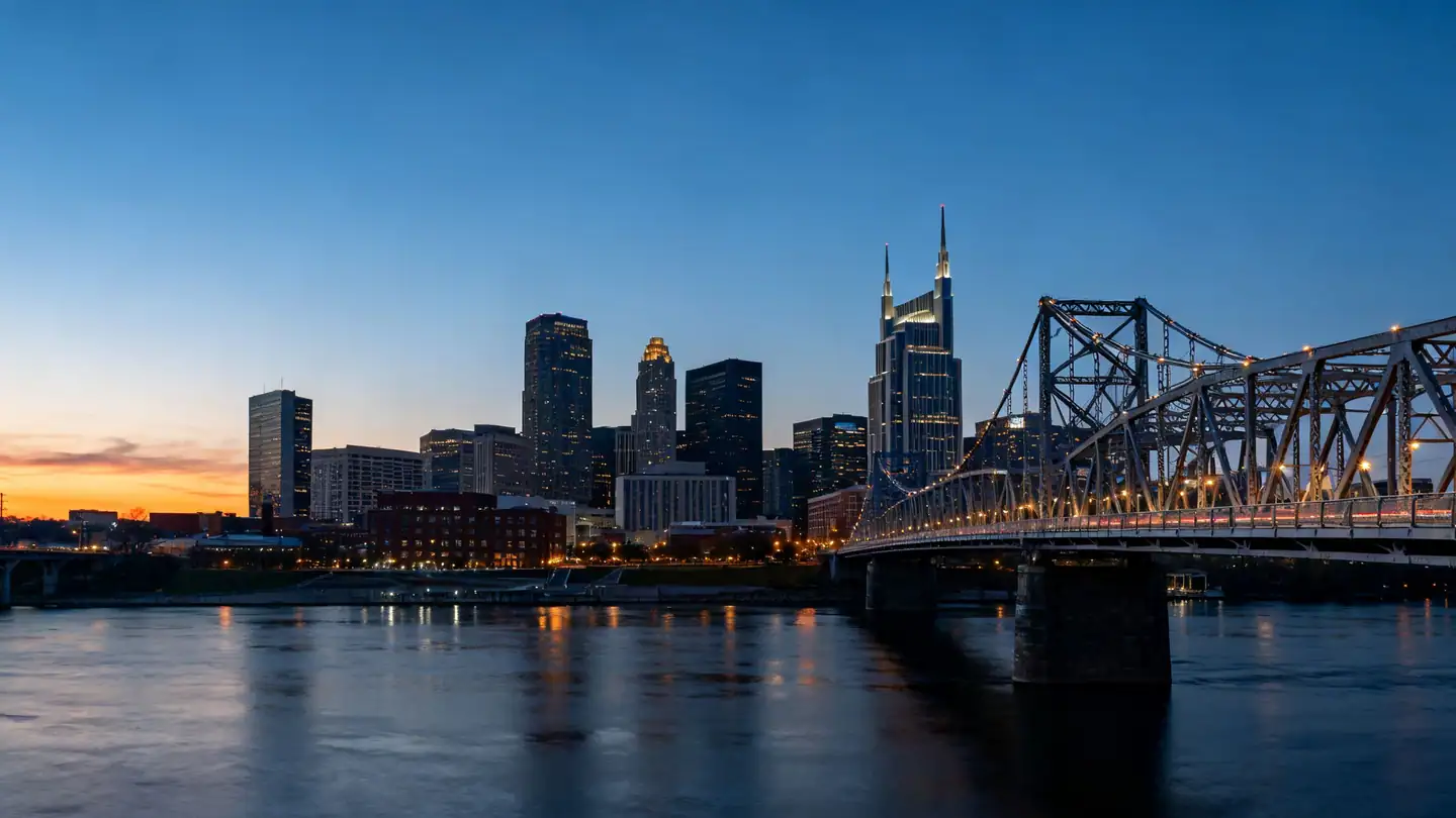 The Nashville skyline across the Cumberland River with a pedestrian truss bridge at dusk