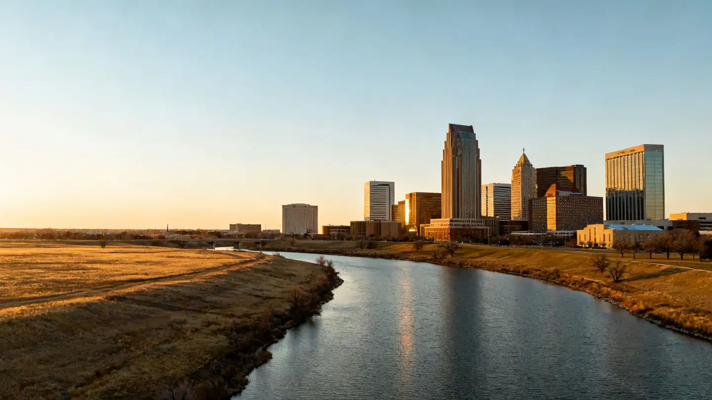 The Oklahoma City skyline over a river with open prairie sky at sunset