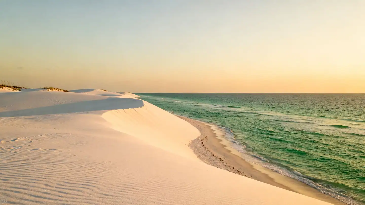 Pensacola Beach: white sugar-sand dunes and emerald Gulf water in golden-hour light