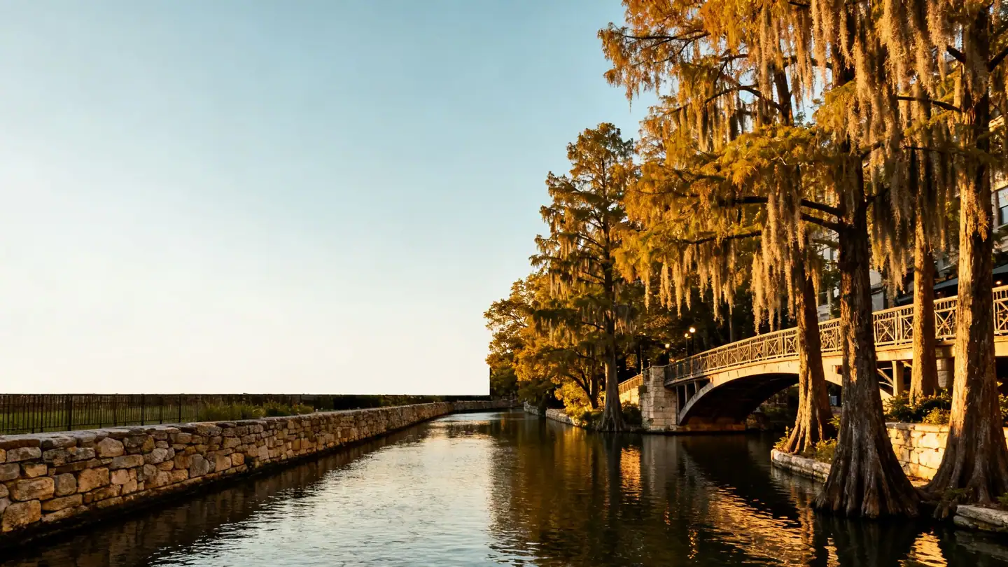 The San Antonio River Walk: a quiet stone-lined river with cypress trees and footbridges in golden-hour light