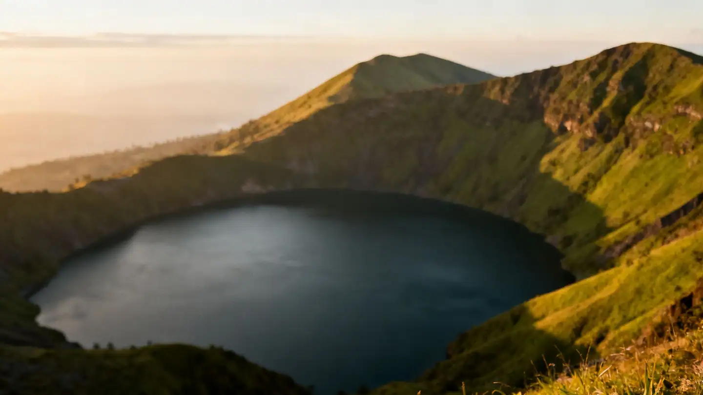 El Salvador: a volcano crater lake surrounded by green hills in golden-hour light