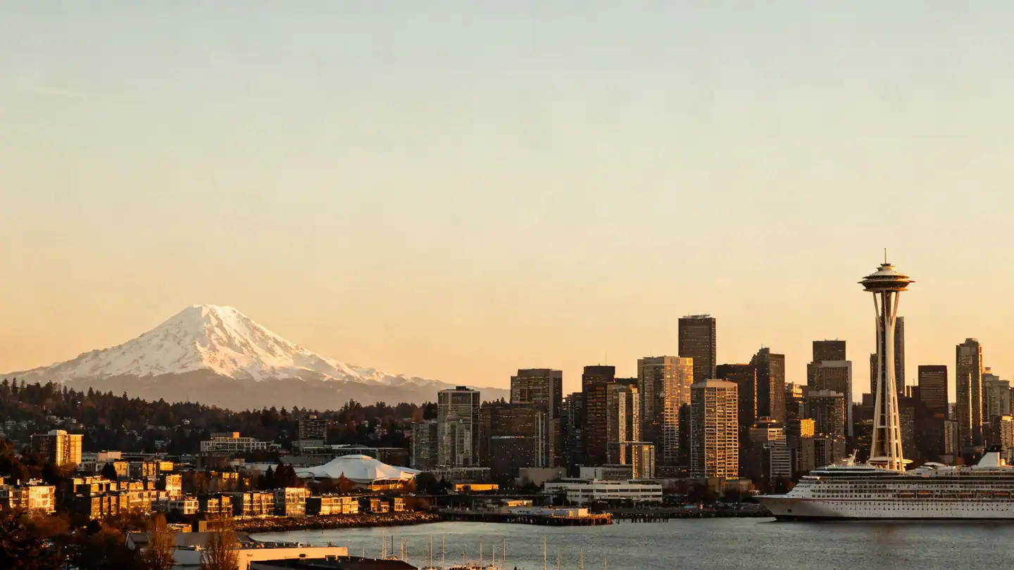 The Seattle skyline over Elliott Bay with snow-capped Mount Rainier in the far distance at sunset