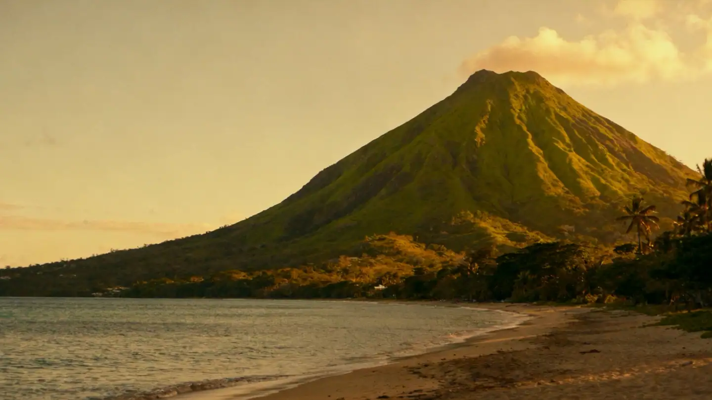 St Kitts: green volcanic peak above a Caribbean coast and a quiet beach in golden-hour light