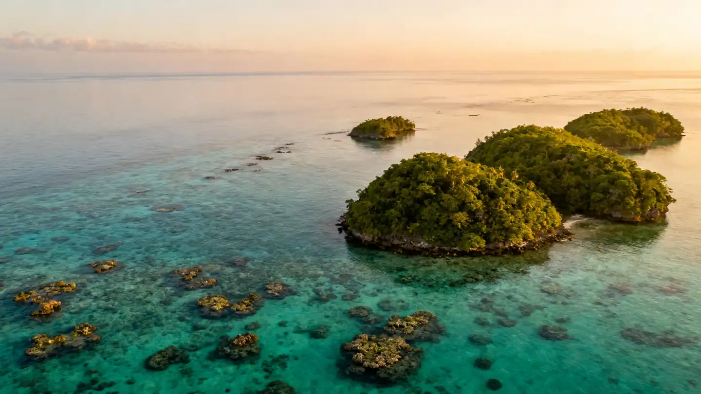 The Grenadines: small green islands and coral reefs in clear turquoise water seen from low altitude in golden-hour light