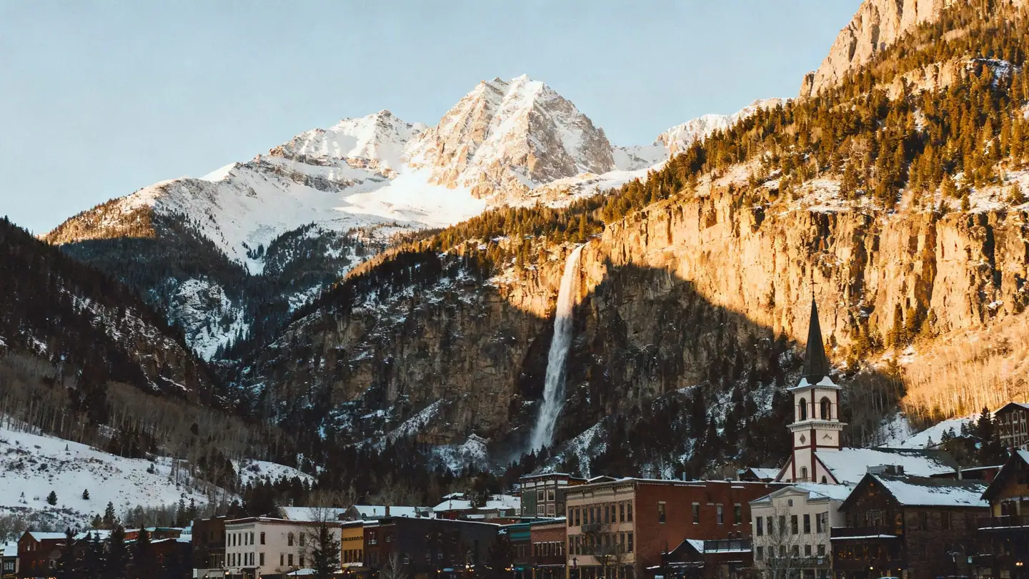 Telluride, Colorado: a Victorian mining town in a box canyon with a tall waterfall and steep snowy peaks in late-afternoon winter light